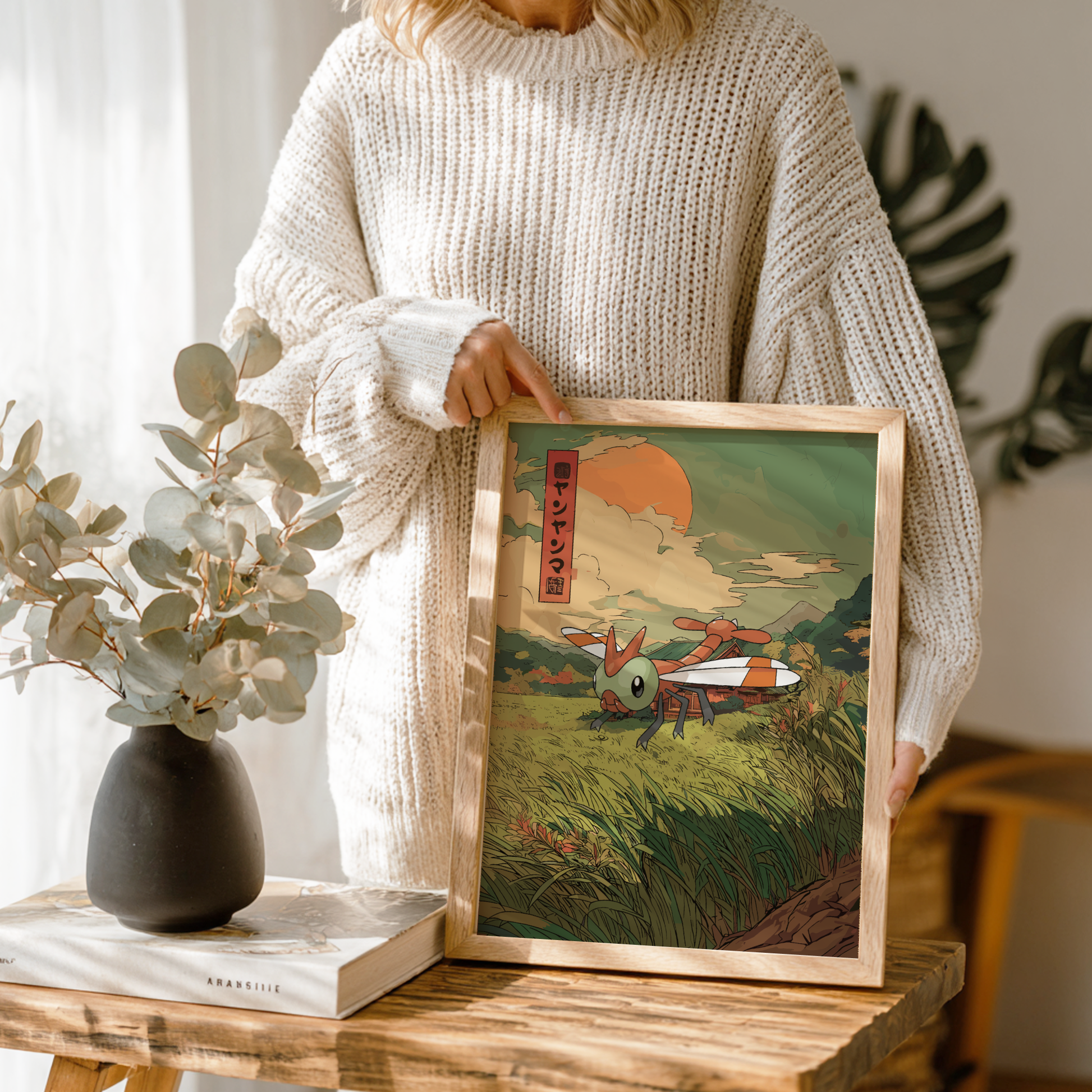 Person holding a framed artwork of a Yanma Pokemon in a natural setting