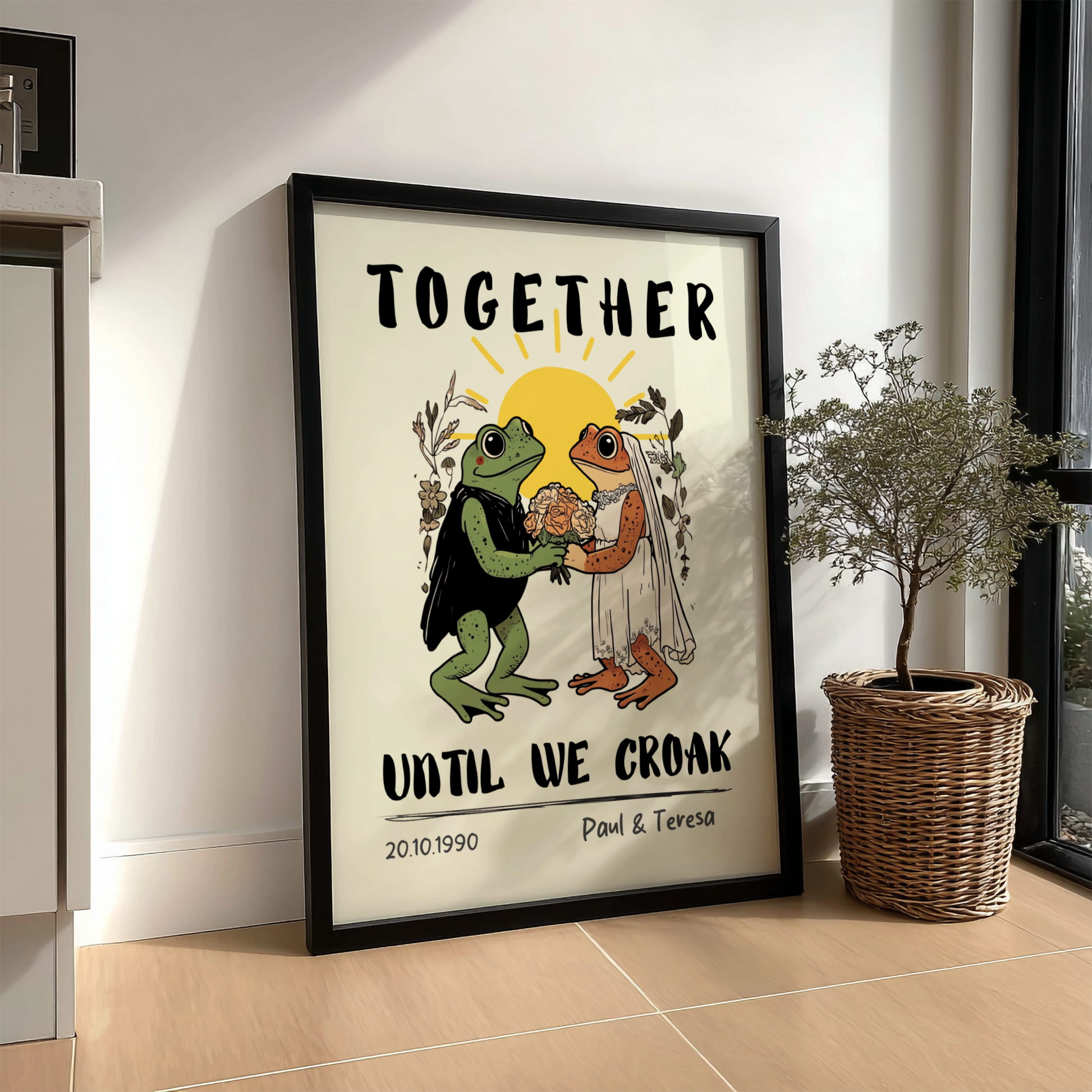 Framed artwork with frogs holding hands and text 'Together until we croak' on a wall.