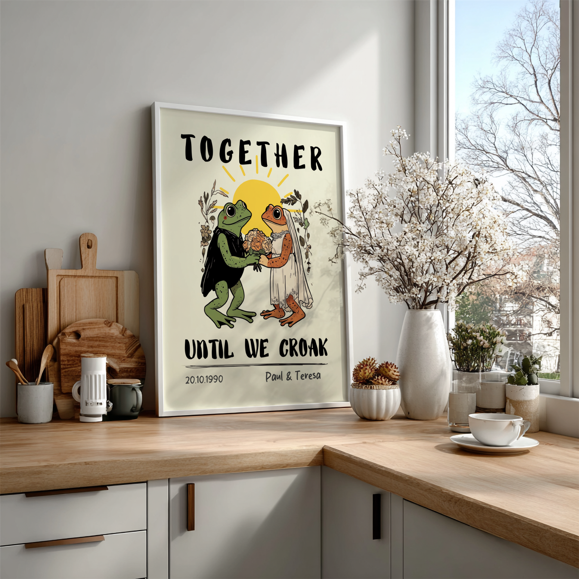 Framed artwork with frogs and text on a kitchen counter