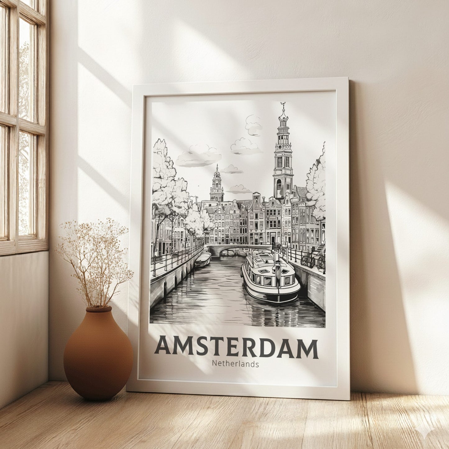 Framed artwork of Amsterdam with a boat on a canal, placed in a bright room with a vase.