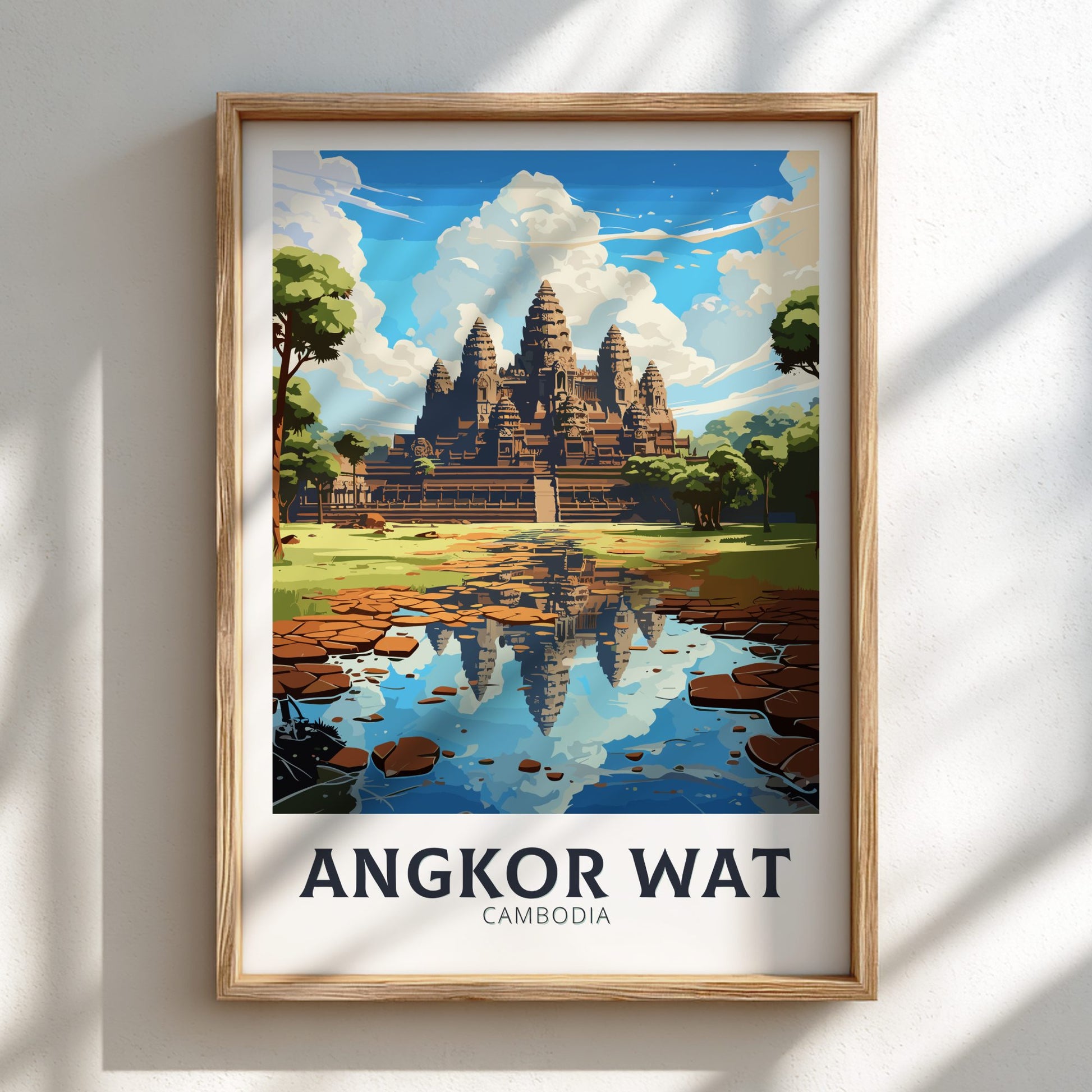 Framed poster of Angkor Wat with a temple reflection in water on a white wall.