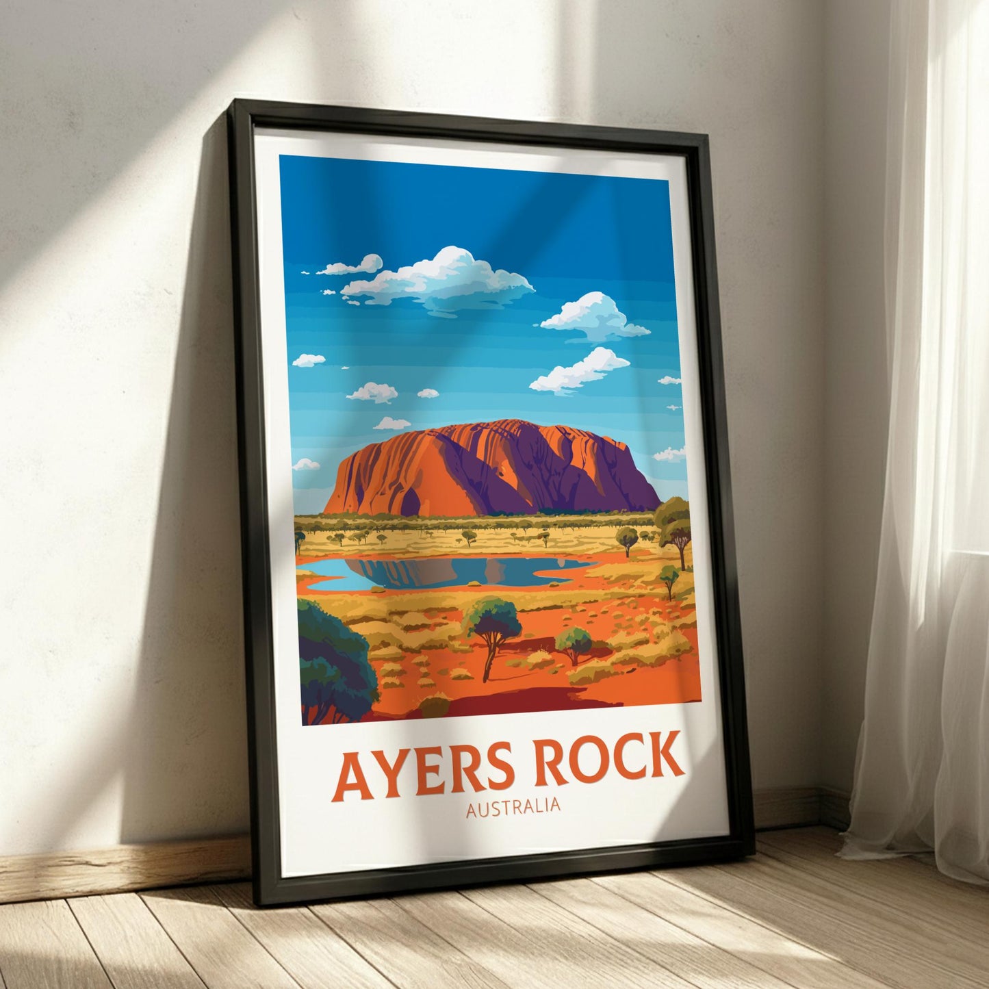 Framed poster of Ayers Rock with a scenic landscape on a wall.