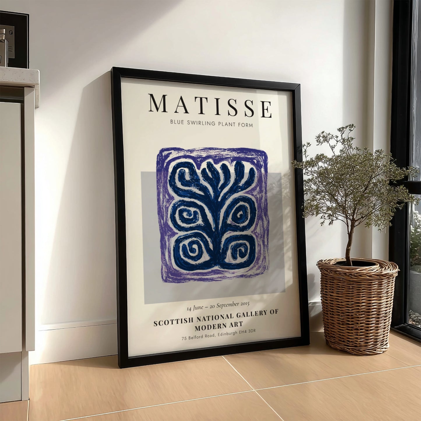 Framed Matisse art print on a wall next to a plant