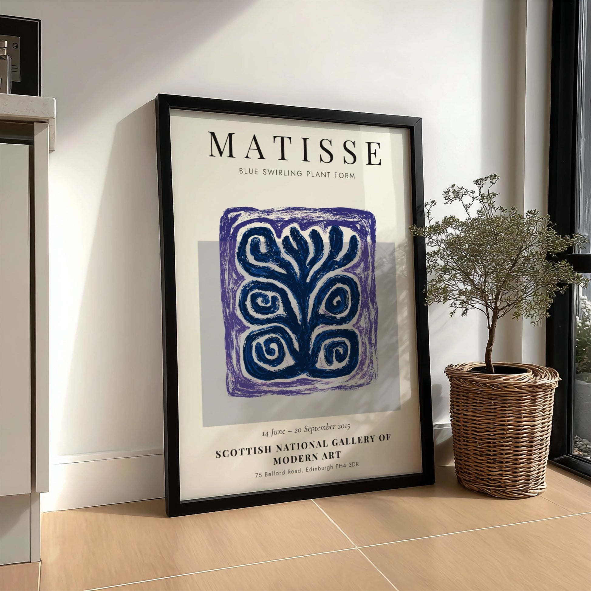 Framed Matisse art print on a wall next to a plant