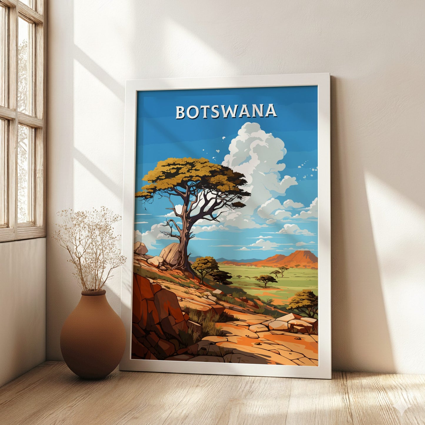 Framed artwork of Botswana with a scenic landscape and 'BOTSWANA' text, placed on a wooden floor.