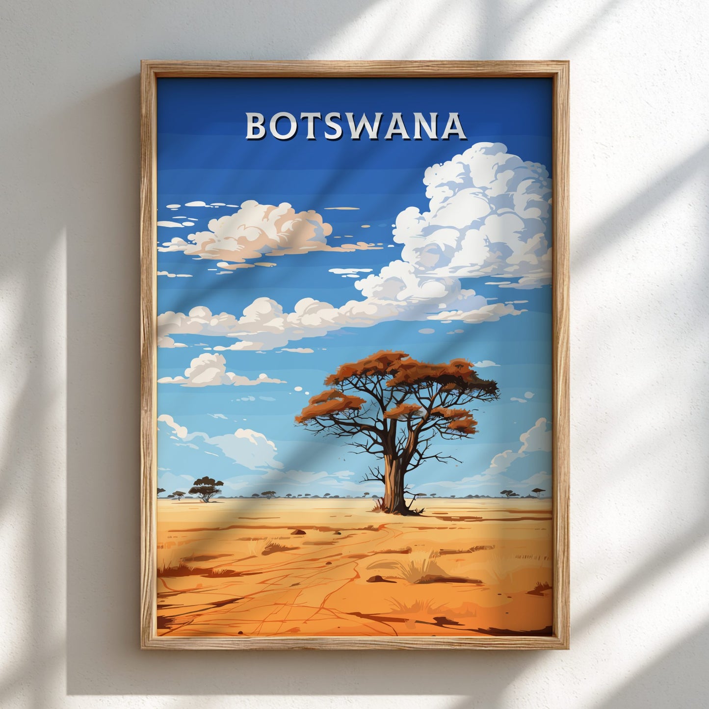 Framed artwork of a desert landscape with a tree and 'Botswana' text on a blue sky background.