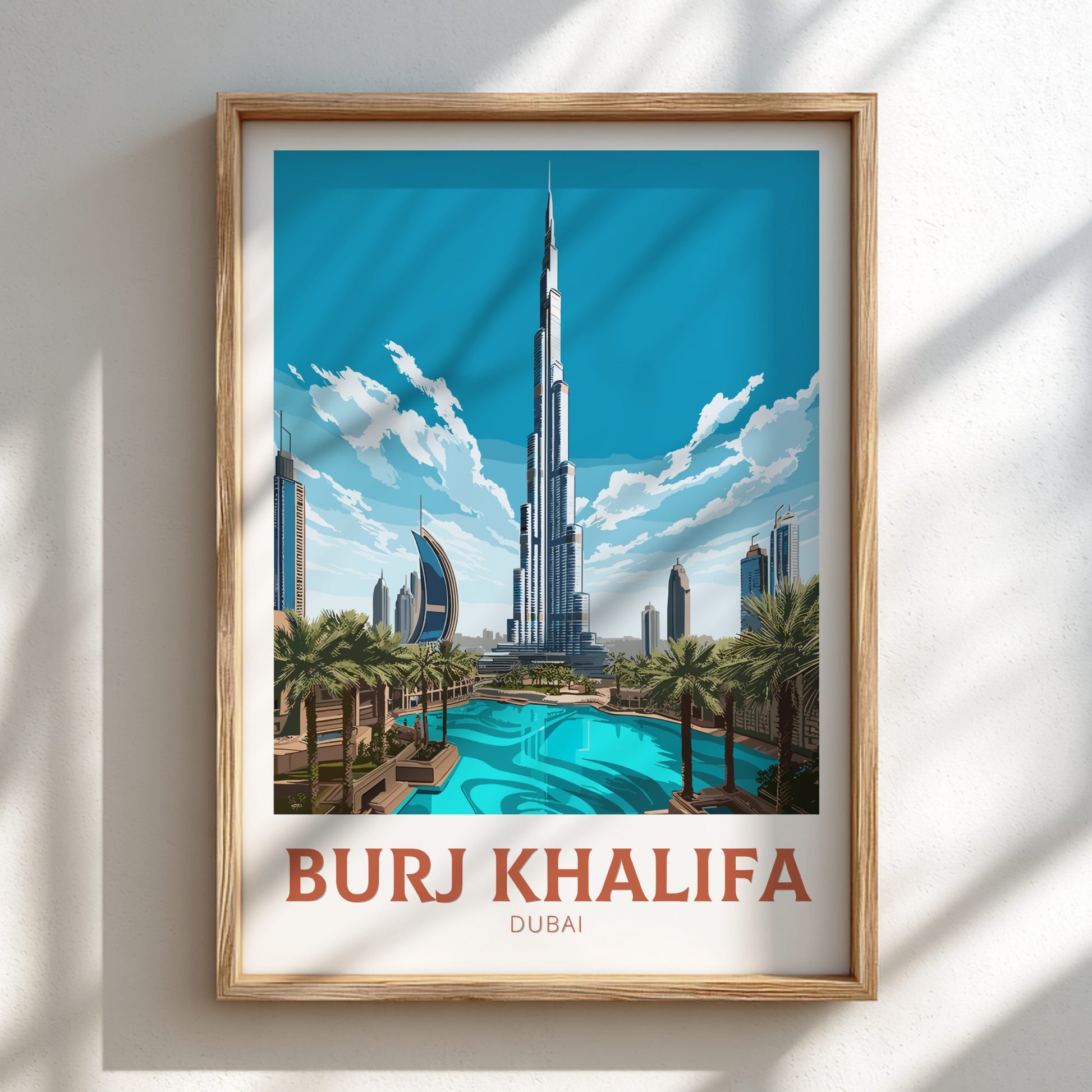 Framed poster of Burj Khalifa with a pool and palm trees on a white wall.