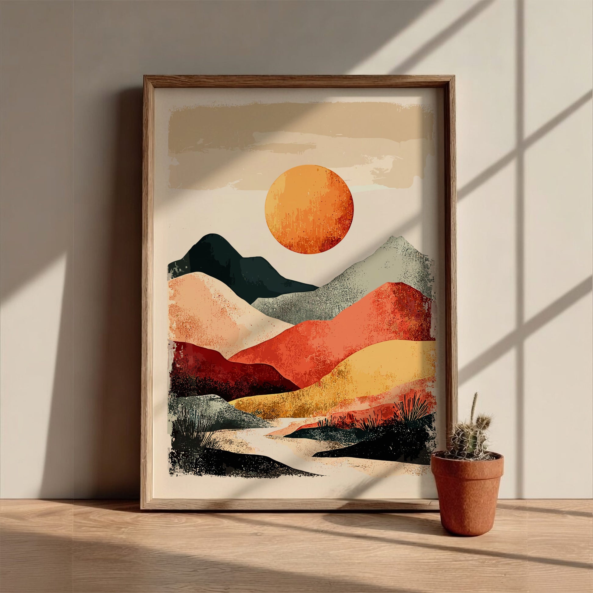 Framed abstract landscape art on a wooden surface with a potted plant.