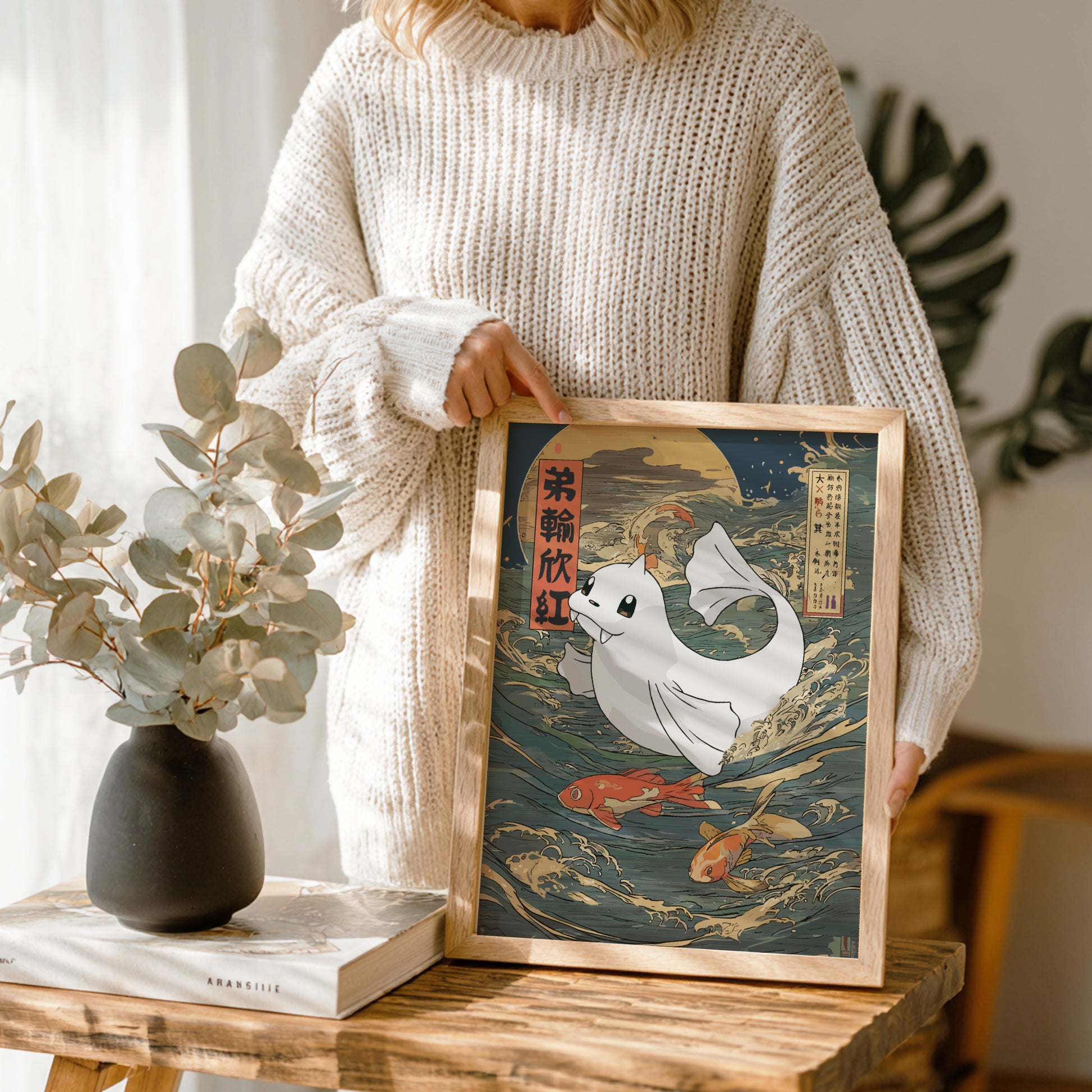 Person holding a framed artwork of Dewgong Pokemon with fish on a wooden table.