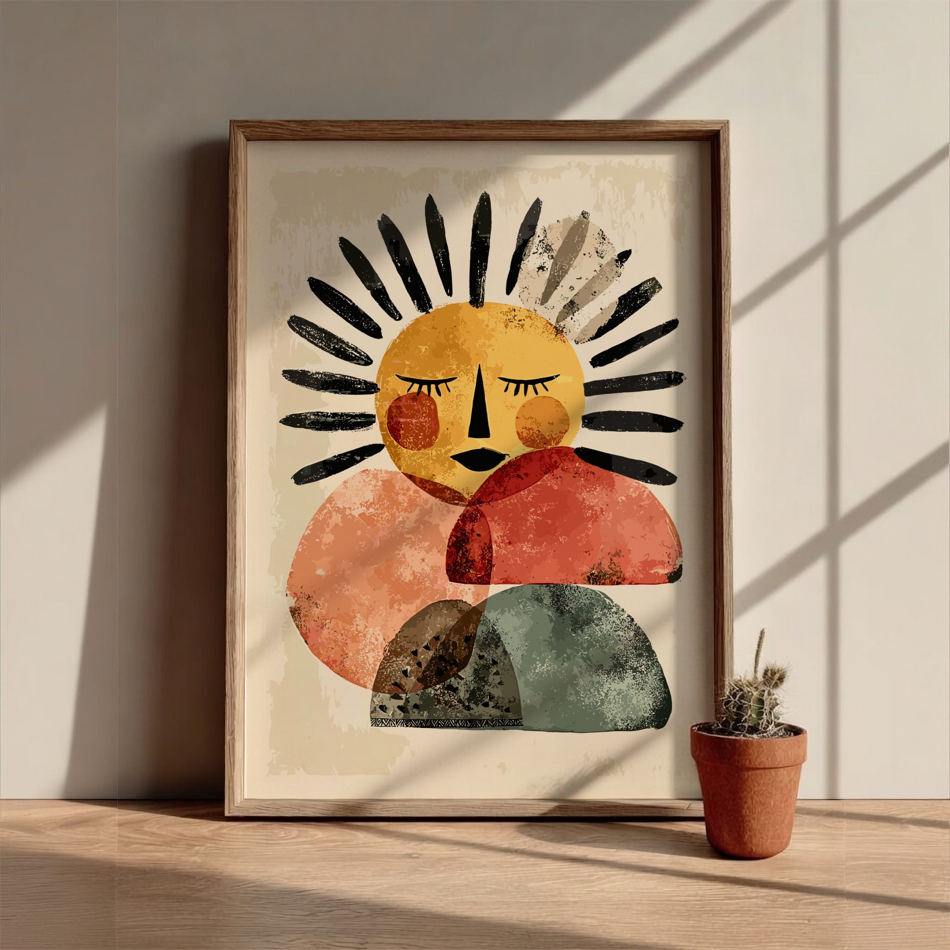 Framed abstract art print of a sun-like figure on a wall with a potted plant below.
