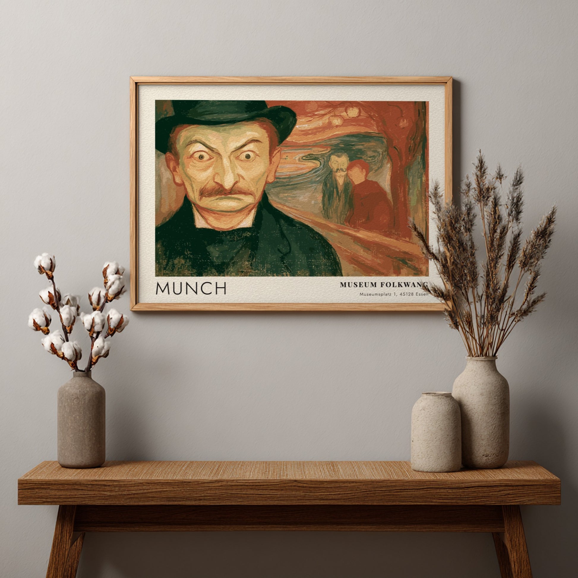 Exhibition poster featuring a wide-eyed man by Munch in a wooden frame display.