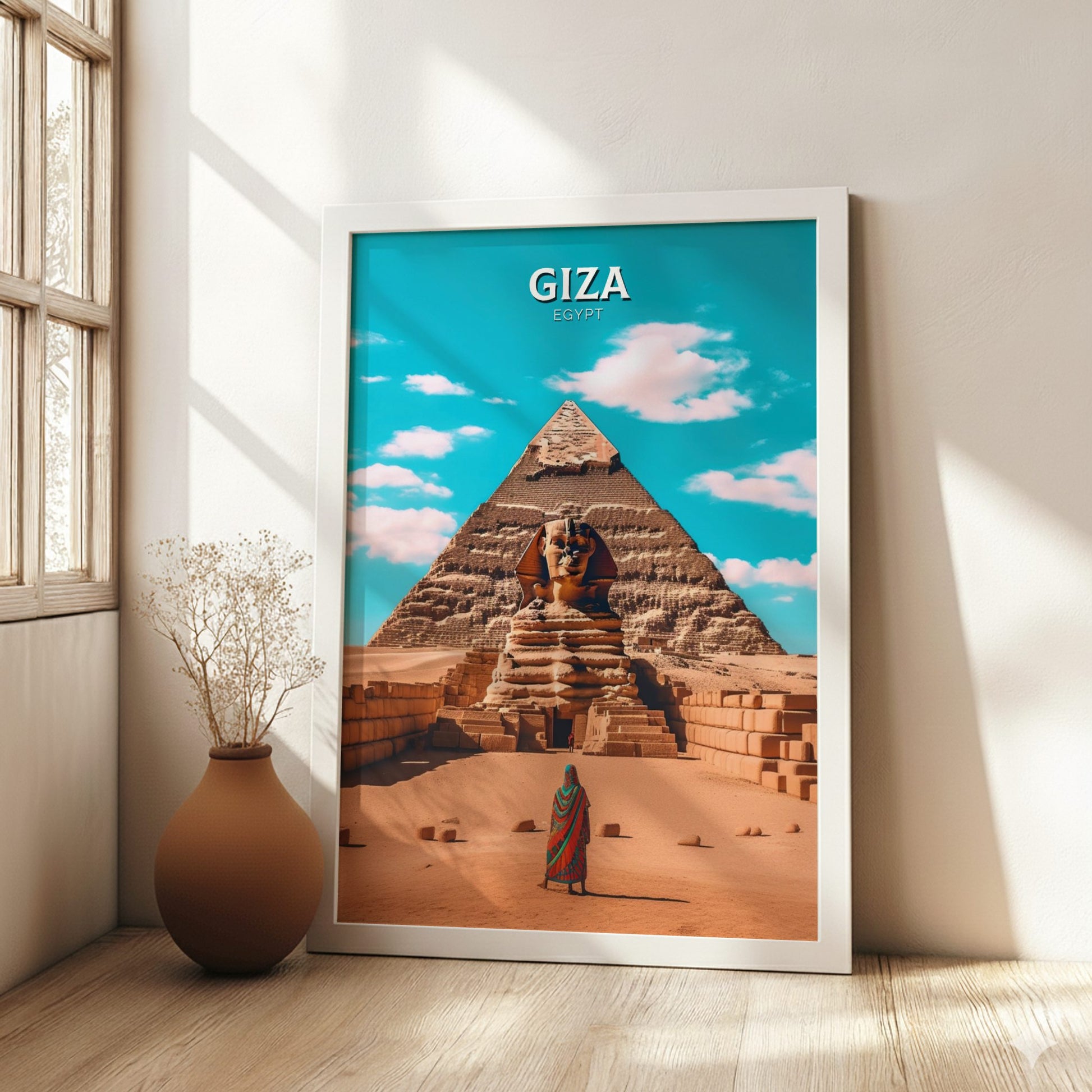 Framed poster of the Pyramids of Giza with a person and Sphinx, placed on a wooden floor.