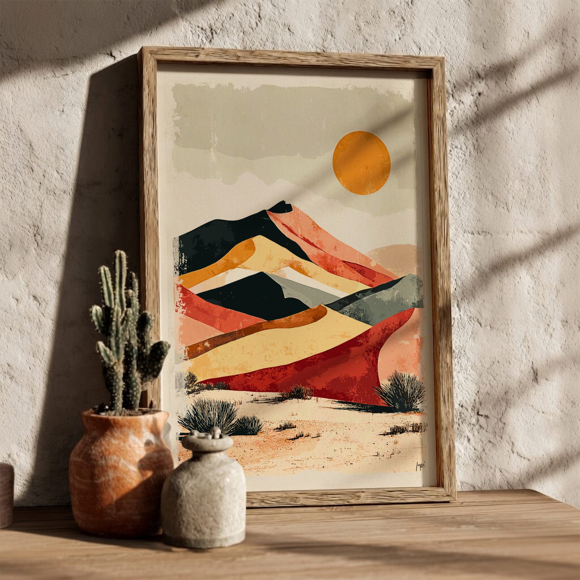 Framed abstract desert landscape art on a wall with a cactus and vase.