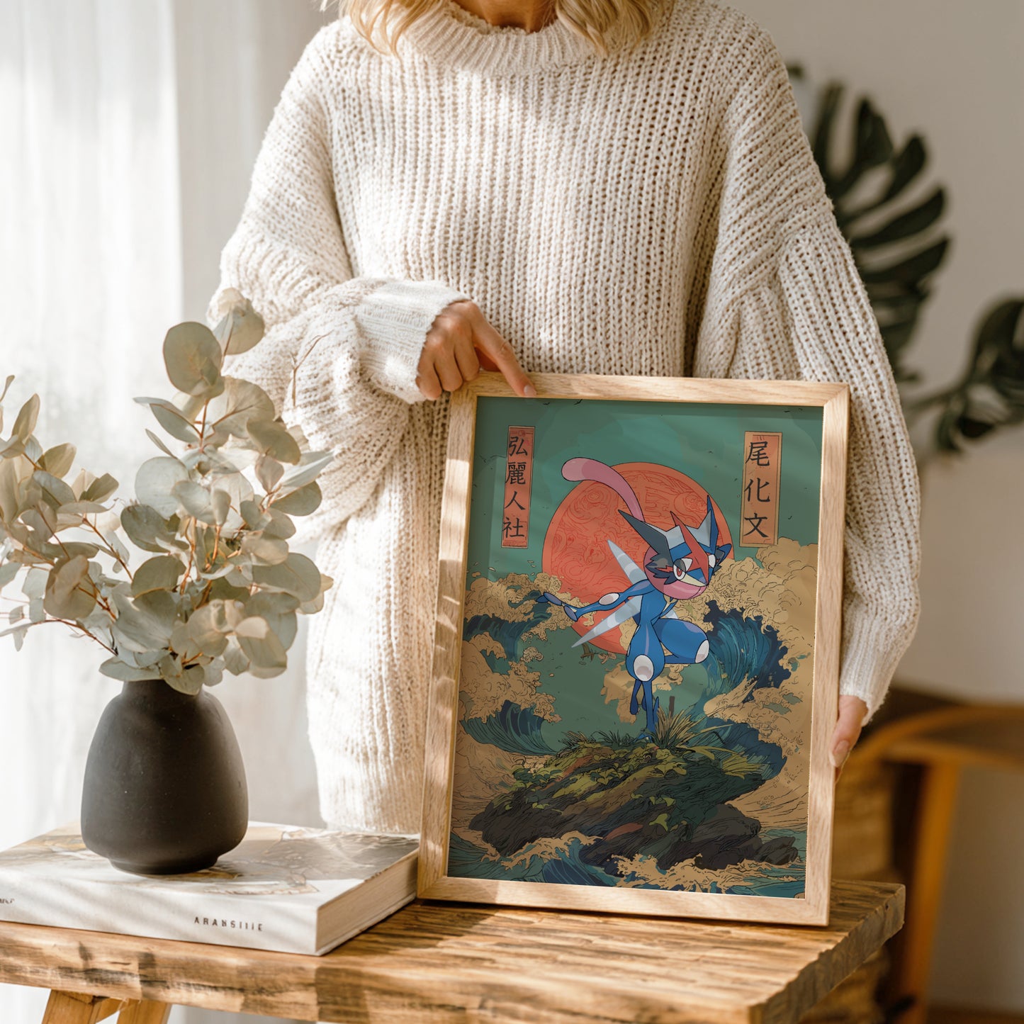 Person holding a framed artwork of Greninja Pokemon with a red sun in a wooden frame.