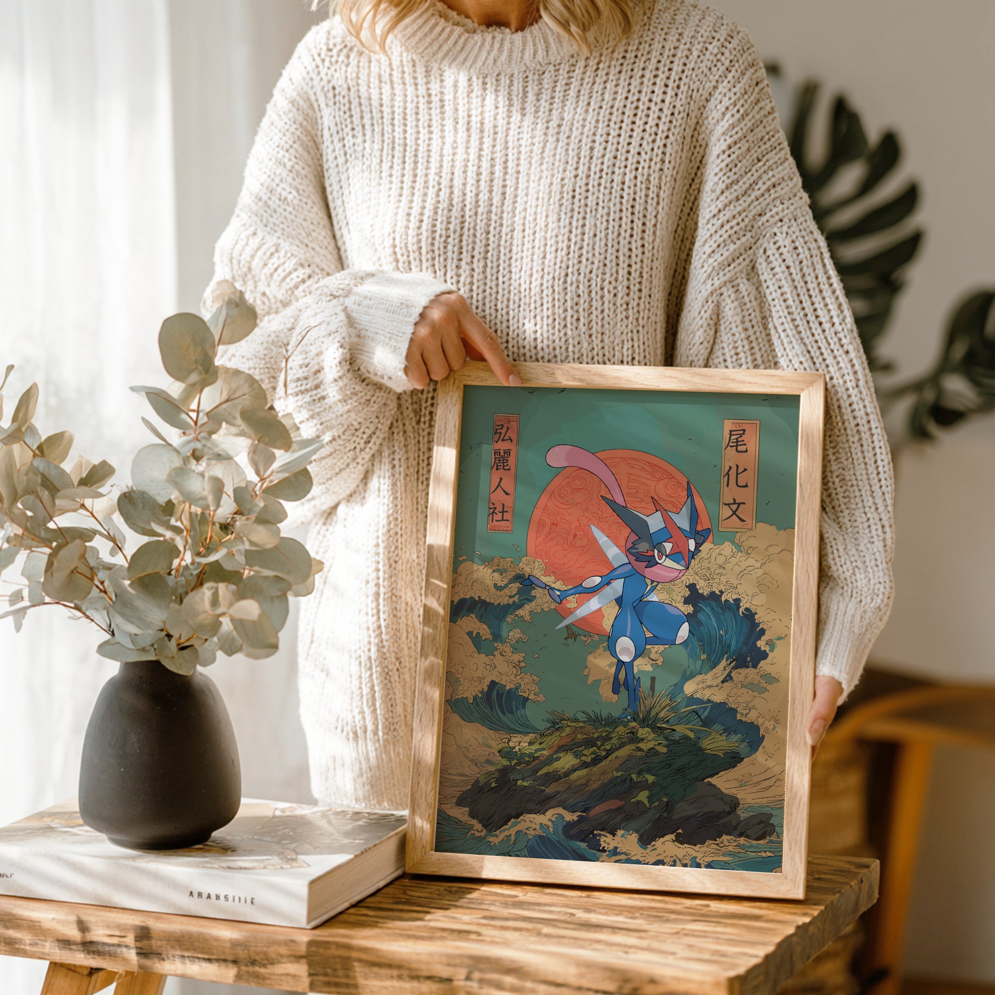 Person holding a framed artwork of Greninja Pokemon with a red sun in a wooden frame.