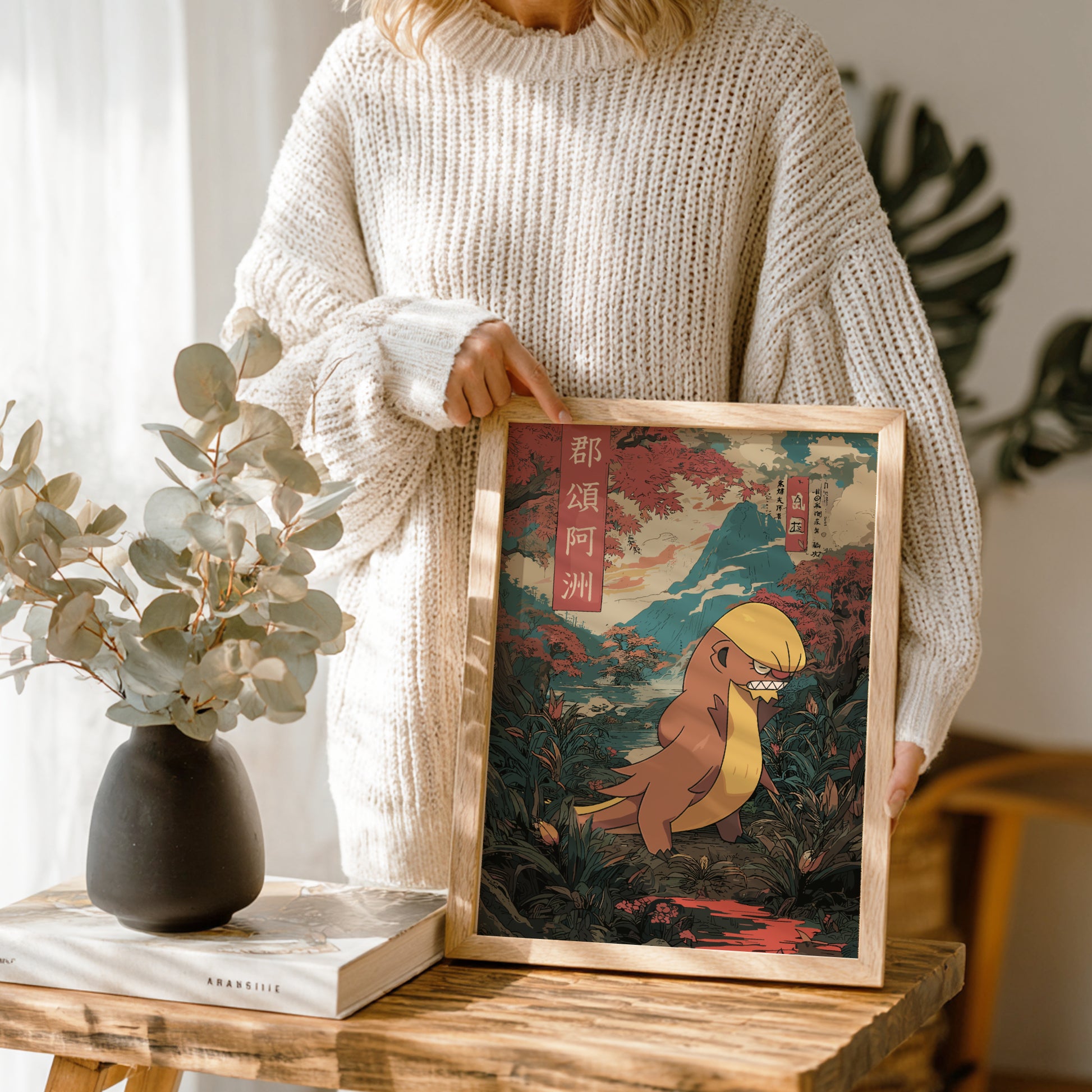 Person holding a framed artwork of Gumshoos Pokemon in a natural setting on a wooden table.