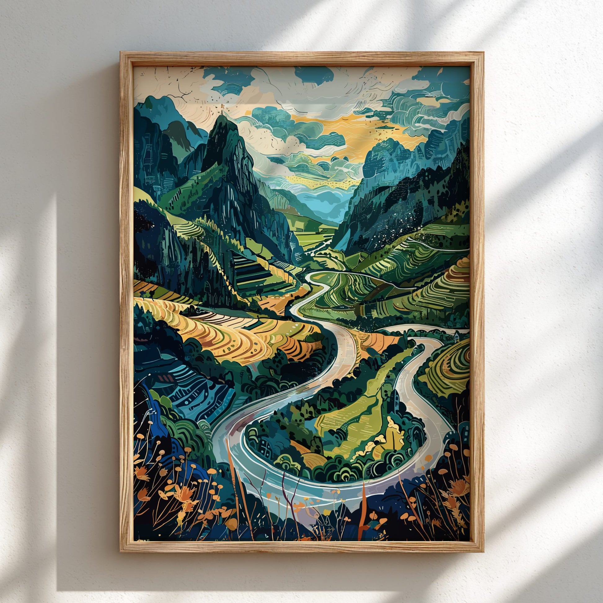 Framed artwork of a mountain landscape with a winding river on a white wall.