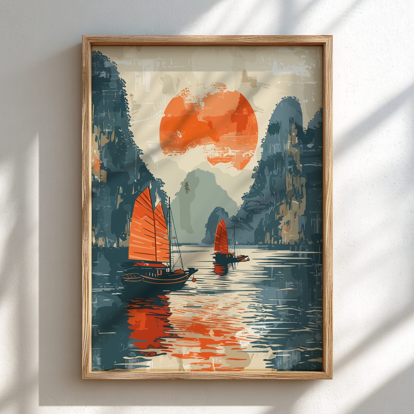 Framed artwork of two sailboats on water with a red sun and mountains in the background.