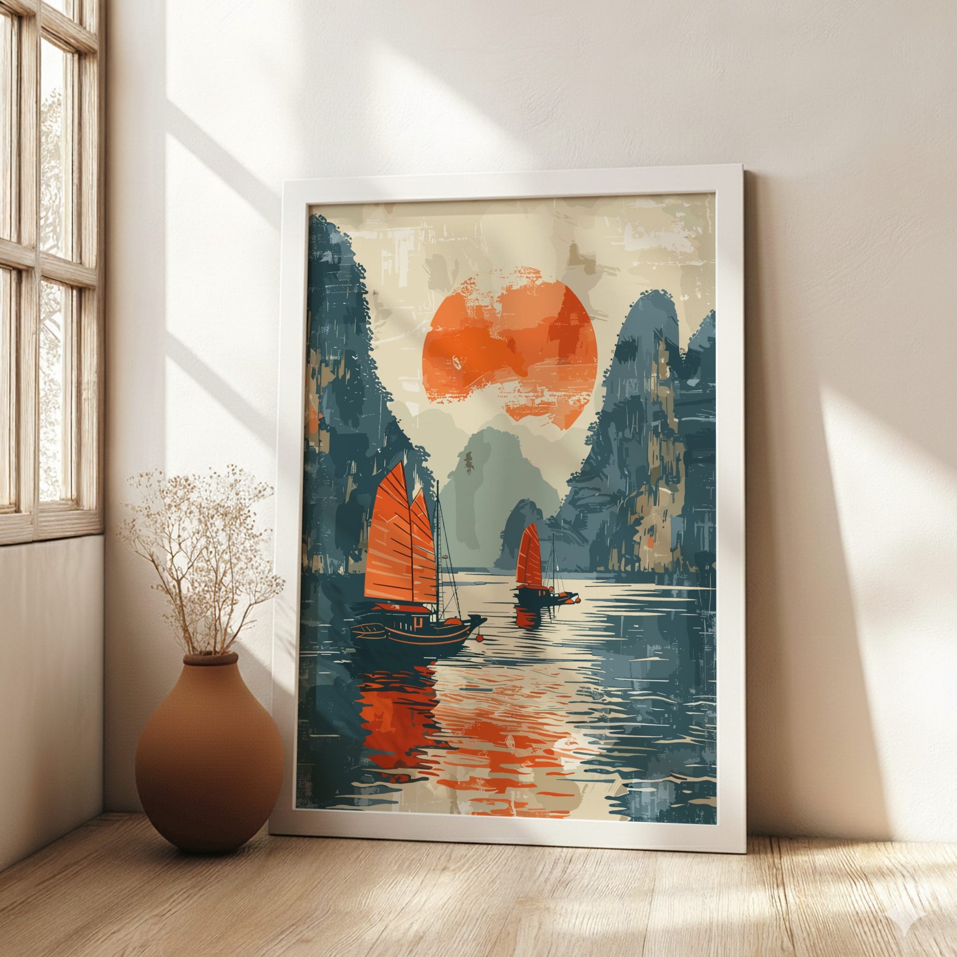 Framed artwork of a sunset over water with sailboats in a room with a vase on the floor.
