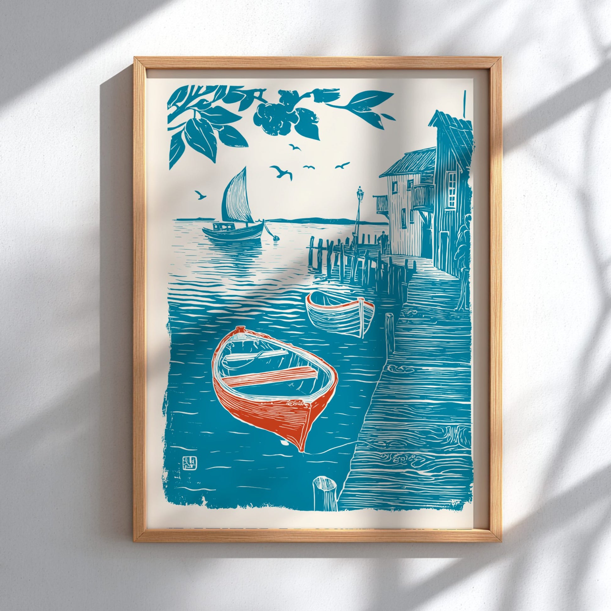 Framed artwork of a coastal scene with boats and buildings on a white wall.