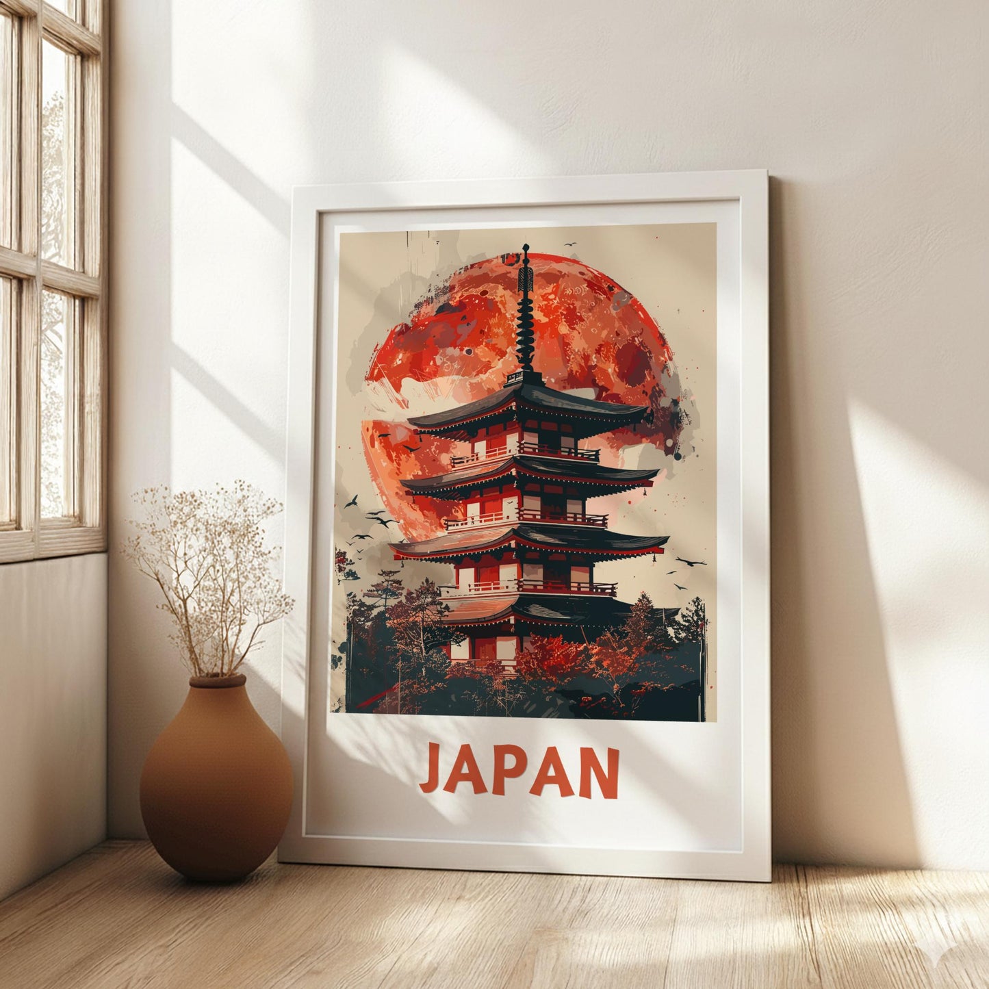 Framed artwork of a Japanese temple with a red moon in a room with a vase and window.