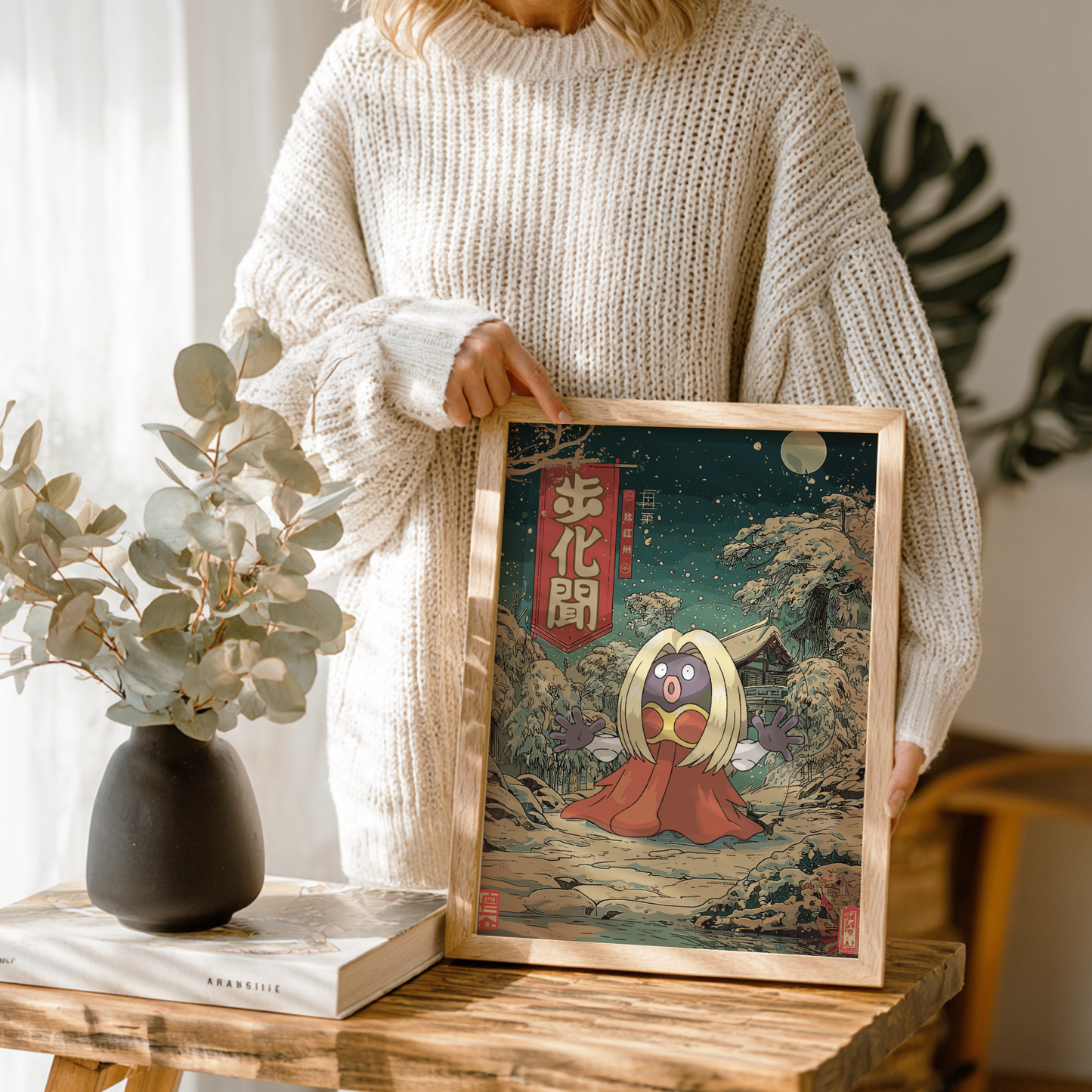 Person holding a framed artwork with Jynx Pokemon, in a home setting.