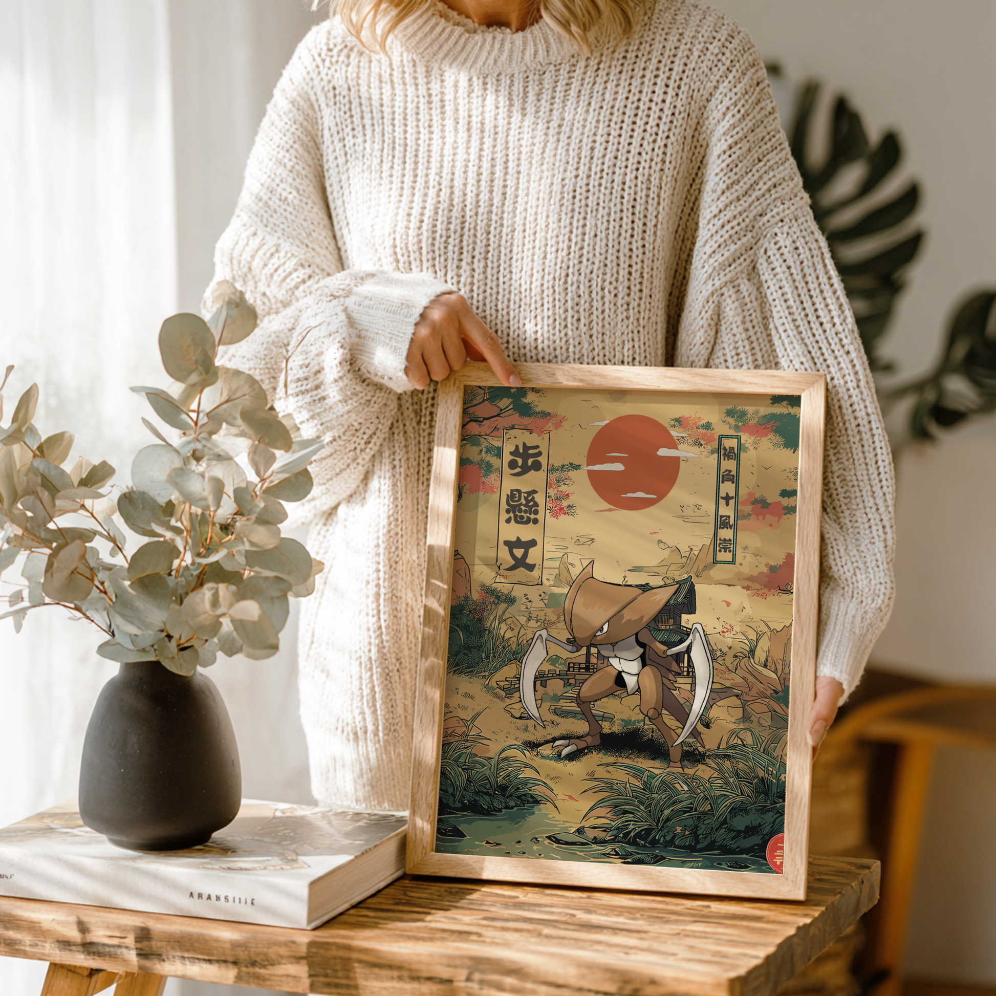 Person holding a framed artwork of Kabutops Pokemon in a home setting