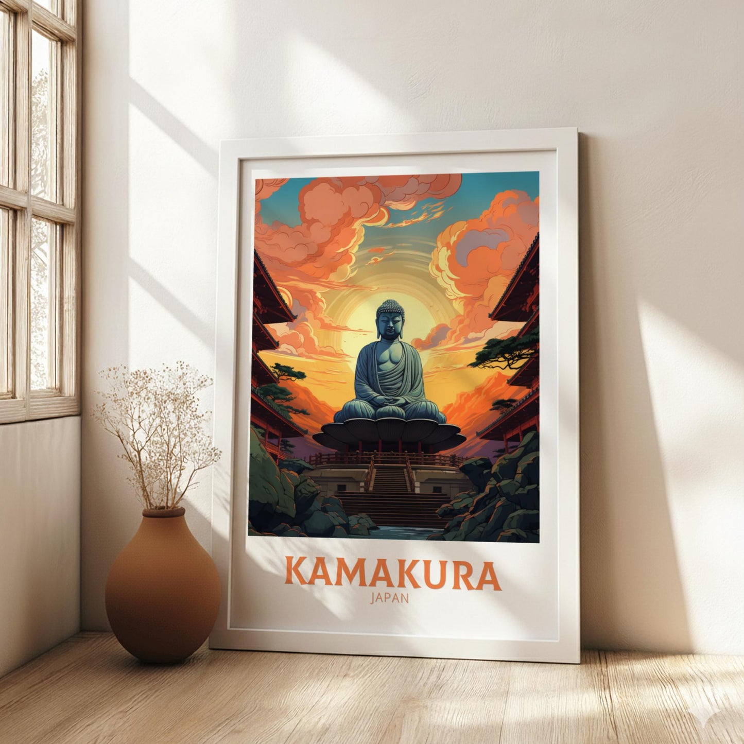 Framed poster of a Buddha statue with 'Kamakura, Japan' text in a room with a vase and plant.