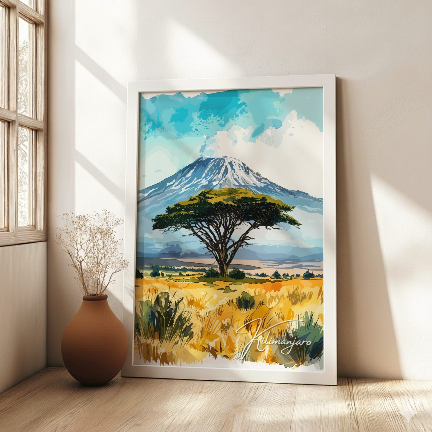 Framed artwork of a landscape with a tree and mountain in a room with natural light.