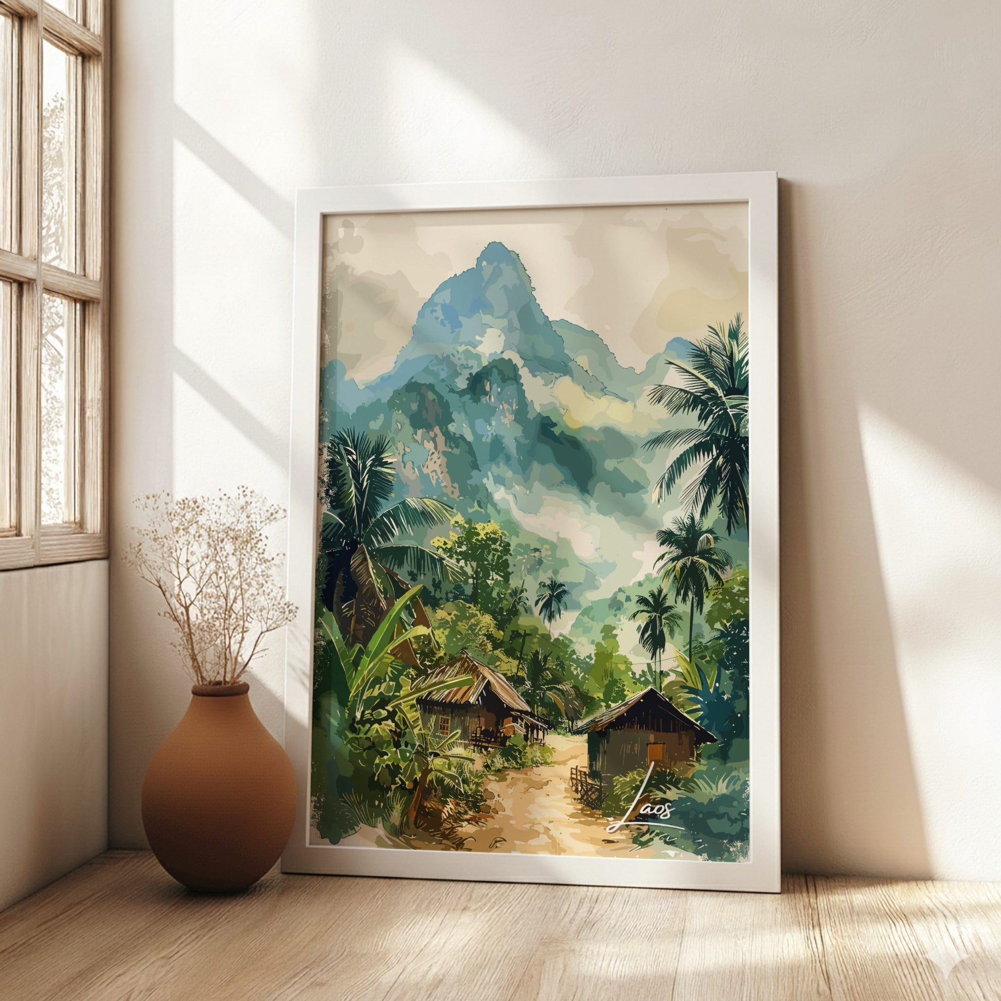 Framed painting of a tropical landscape with mountains and huts in a room with a vase on the floor.