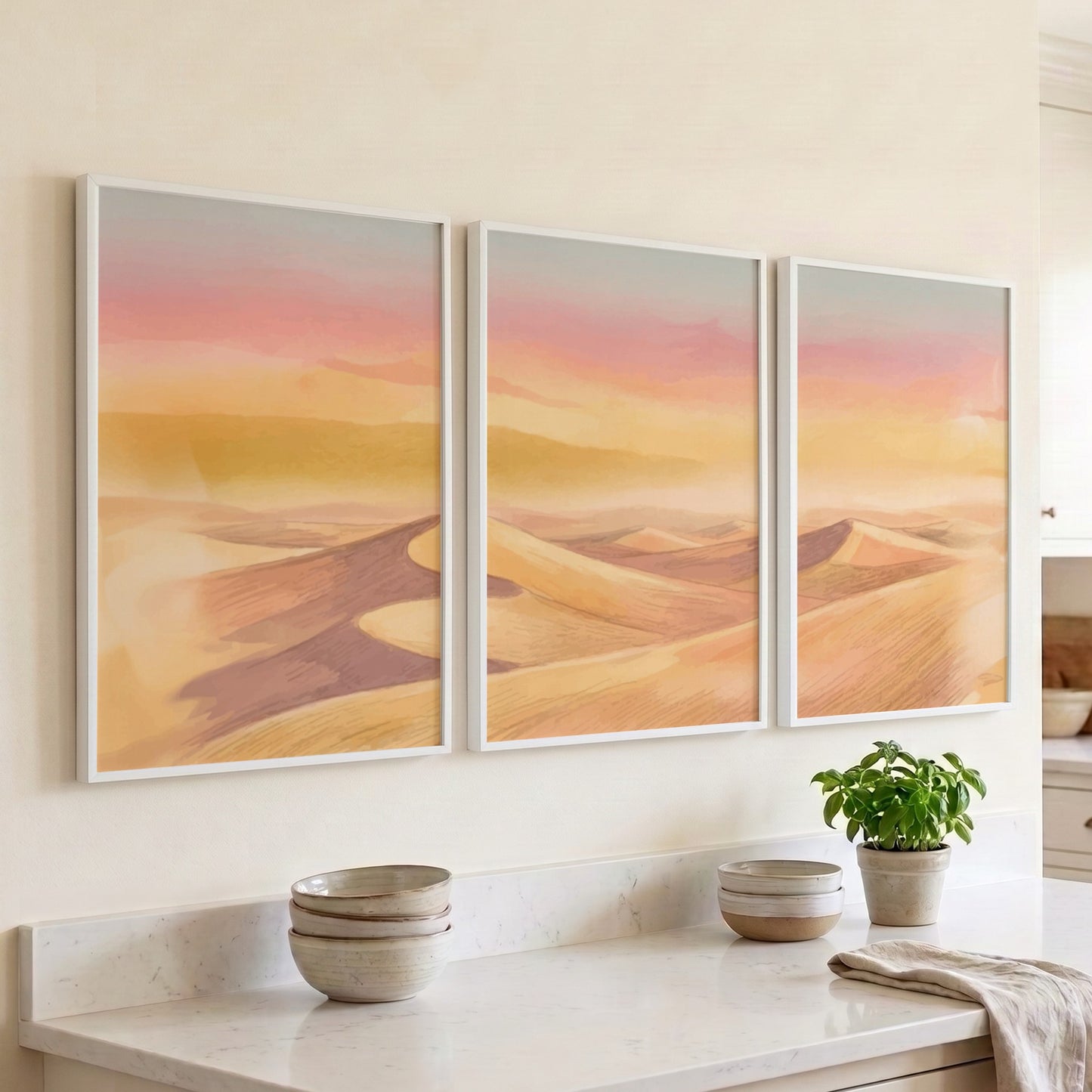 Three framed landscape prints showing golden desert dunes under a soft sunset sky