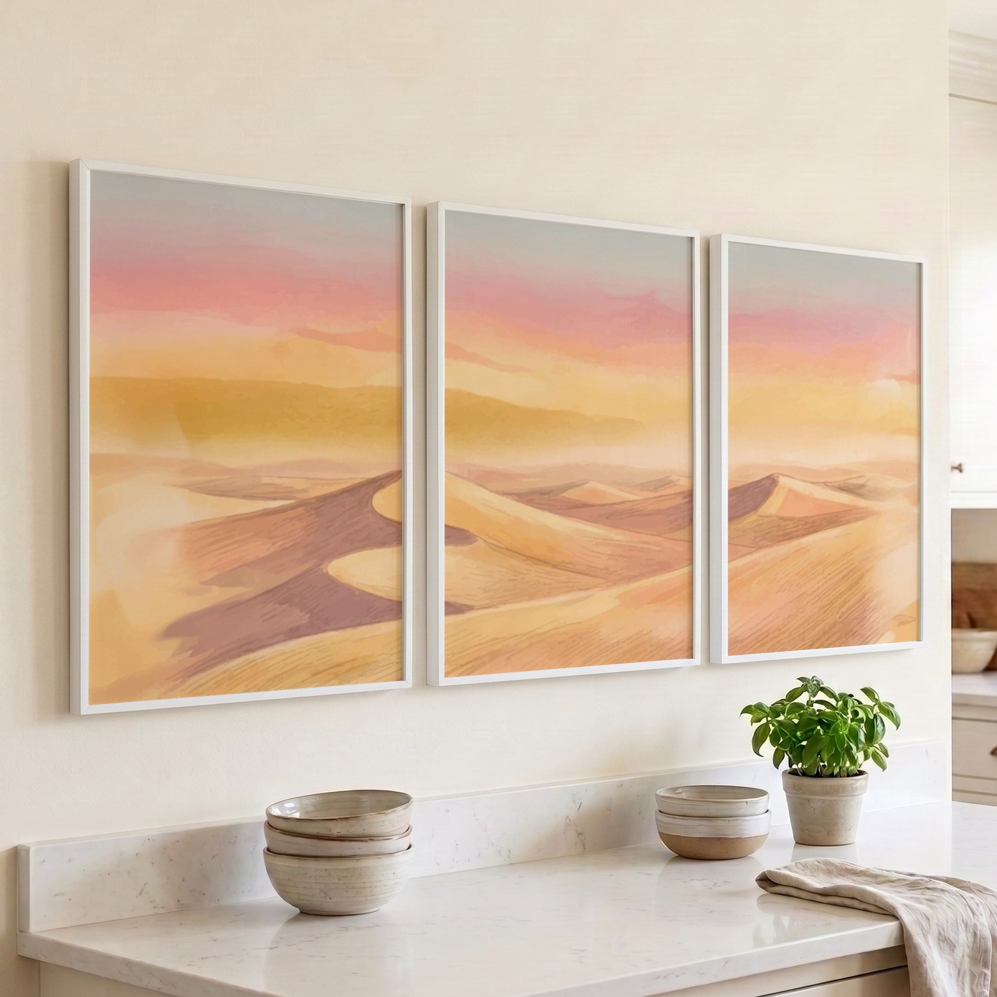 Three framed landscape prints showing golden desert dunes under a soft sunset sky