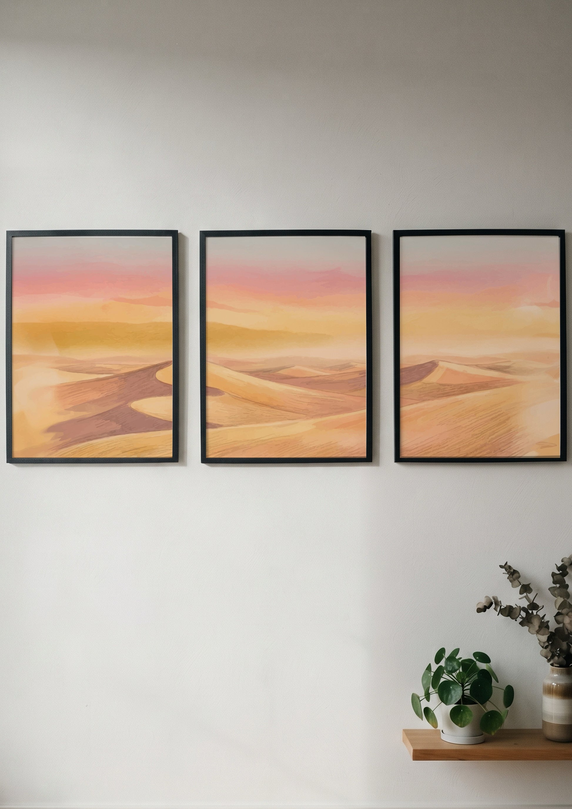 Three framed landscape prints showing golden desert dunes under a soft sunset sky