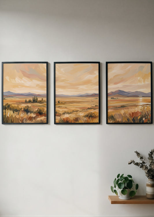Three framed landscape prints showing golden prairies and distant mountains in a painterly style.