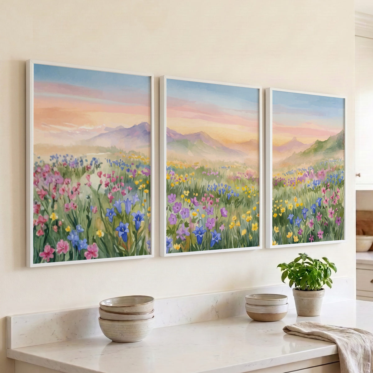 Three framed wildflower meadow watercolour paintings showing pink and purple flowers near mountains.