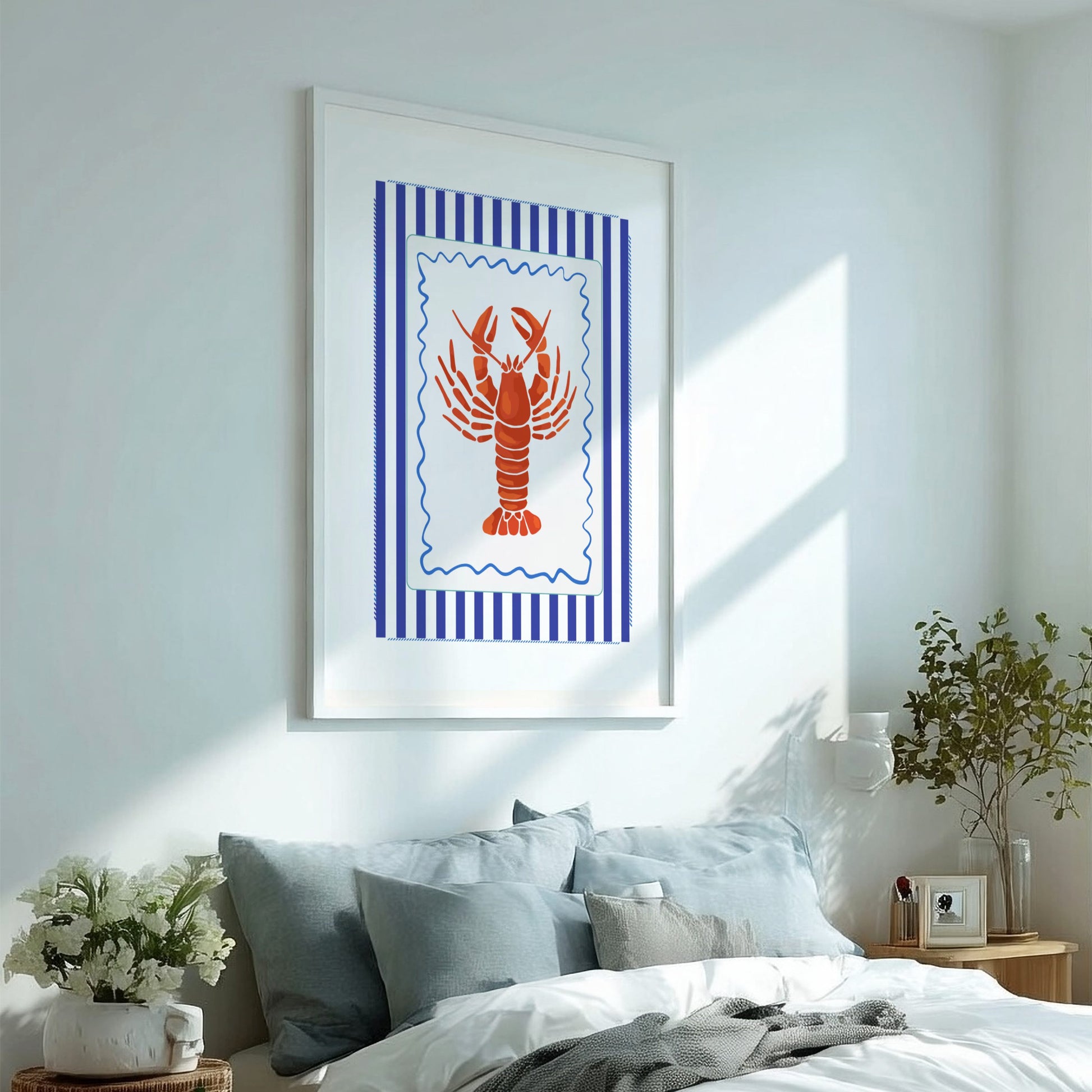 Framed artwork of a red lobster on a blue striped background above a bed with pillows and a plant.
