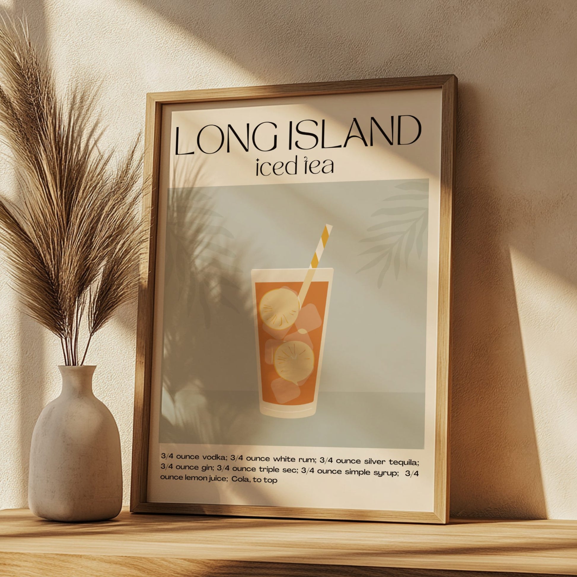 Framed poster of a Long Island iced tea recipe on a wall with a vase and decorative plant.
