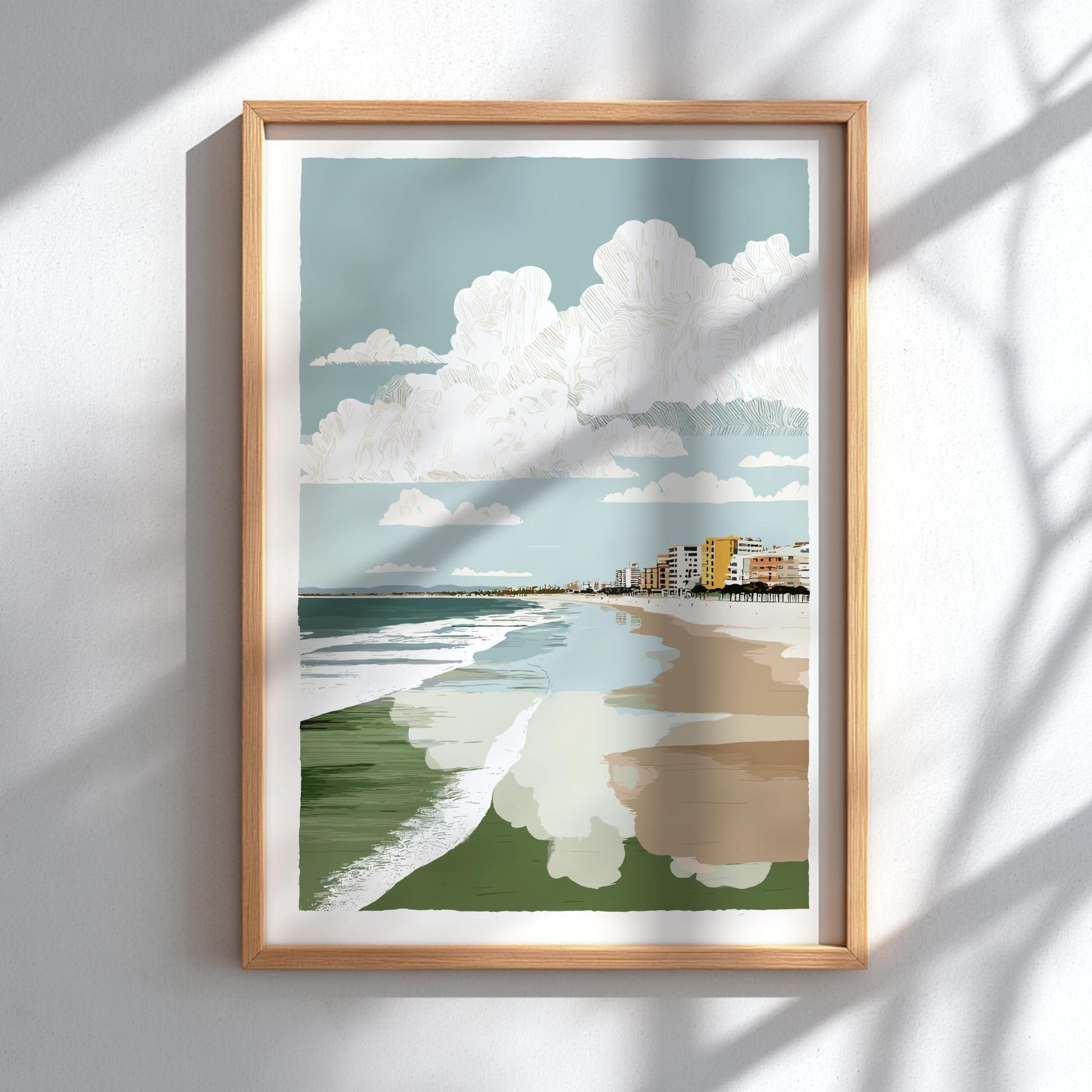 Framed artwork of a beach scene with a blue sky, white clouds, green grass, and a path.