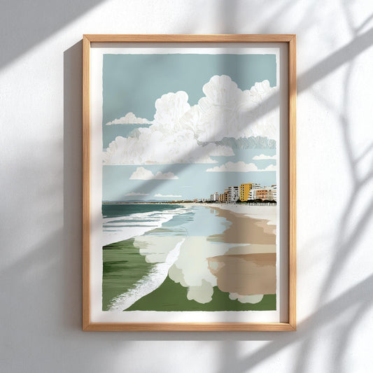 Framed artwork of a beach scene with a blue sky, white clouds, green grass, and a path.