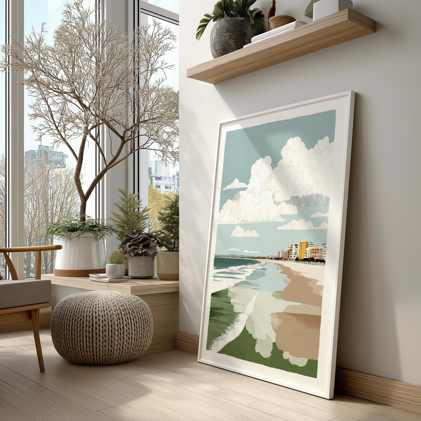 Framed beach artwork on a wall in a room with large windows and indoor plants.