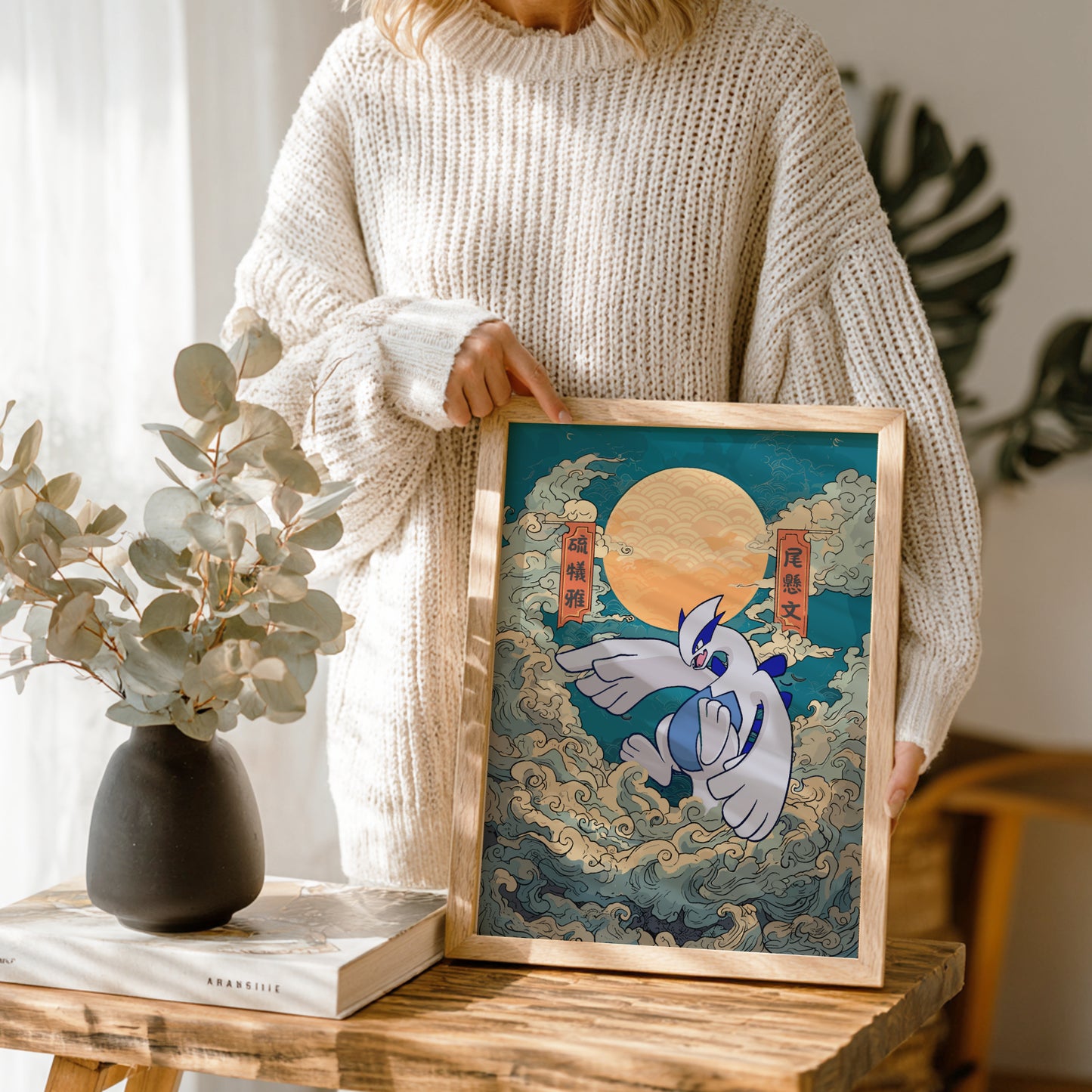 Person holding a framed artwork of Lugia Pokemon with a moon in a wooden frame.