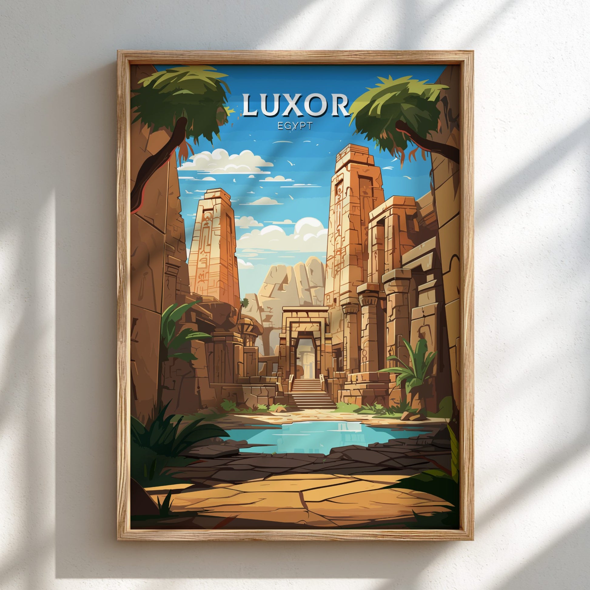 Framed artwork of Luxor Temple with palm trees and a pool on a white wall.