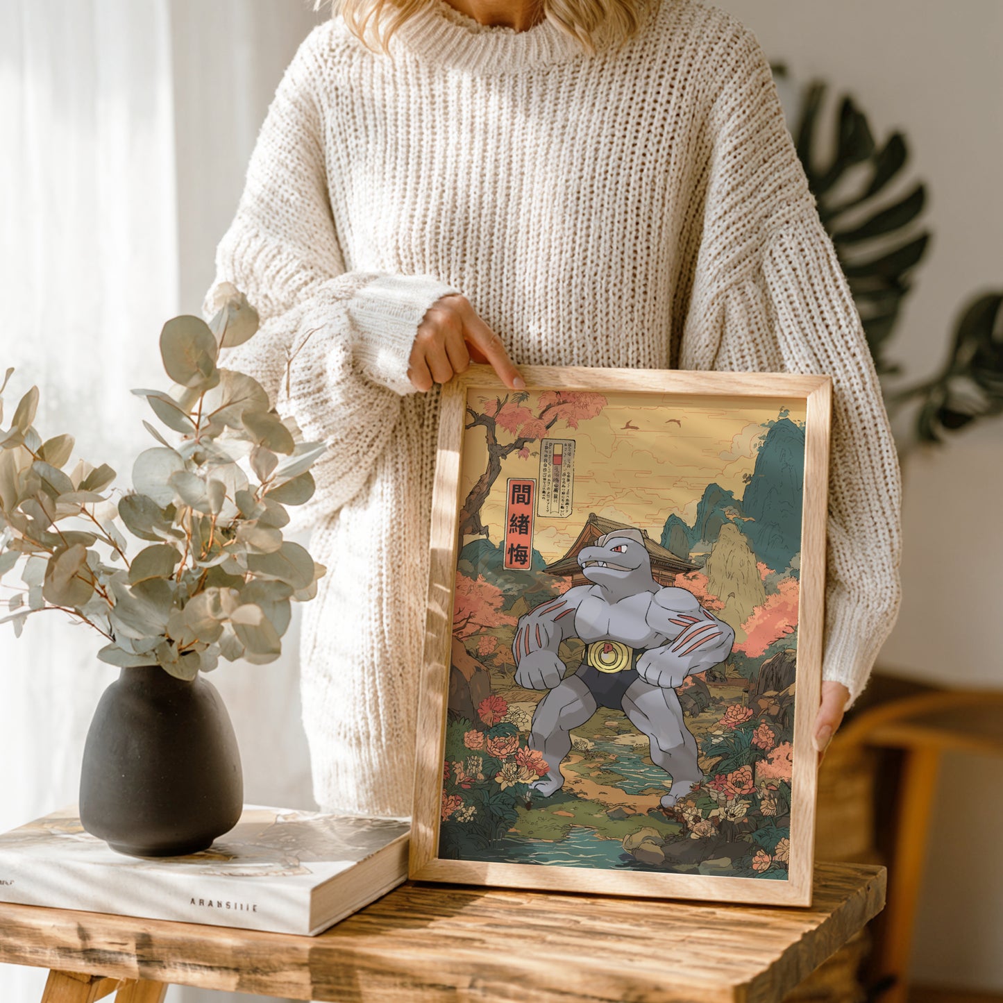 Person holding a framed artwork of Machoke Pokemon in a natural setting