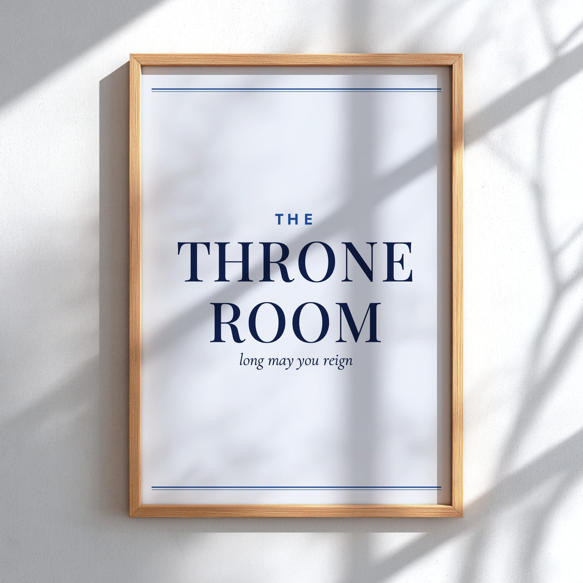 A framed typographic wall art print reading “THE THRONE ROOM” with smaller text “long may you reign,” shown hanging on a light wall with soft shadow overlays.