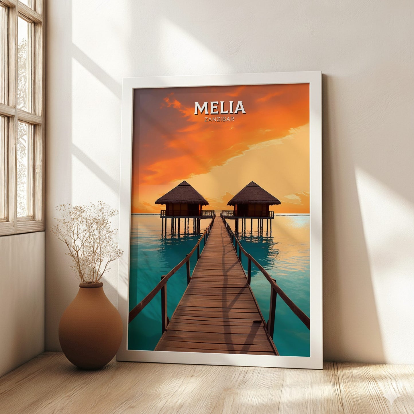 Framed poster of a tropical scene with 'Melia' branding in a room with a wooden floor and window.