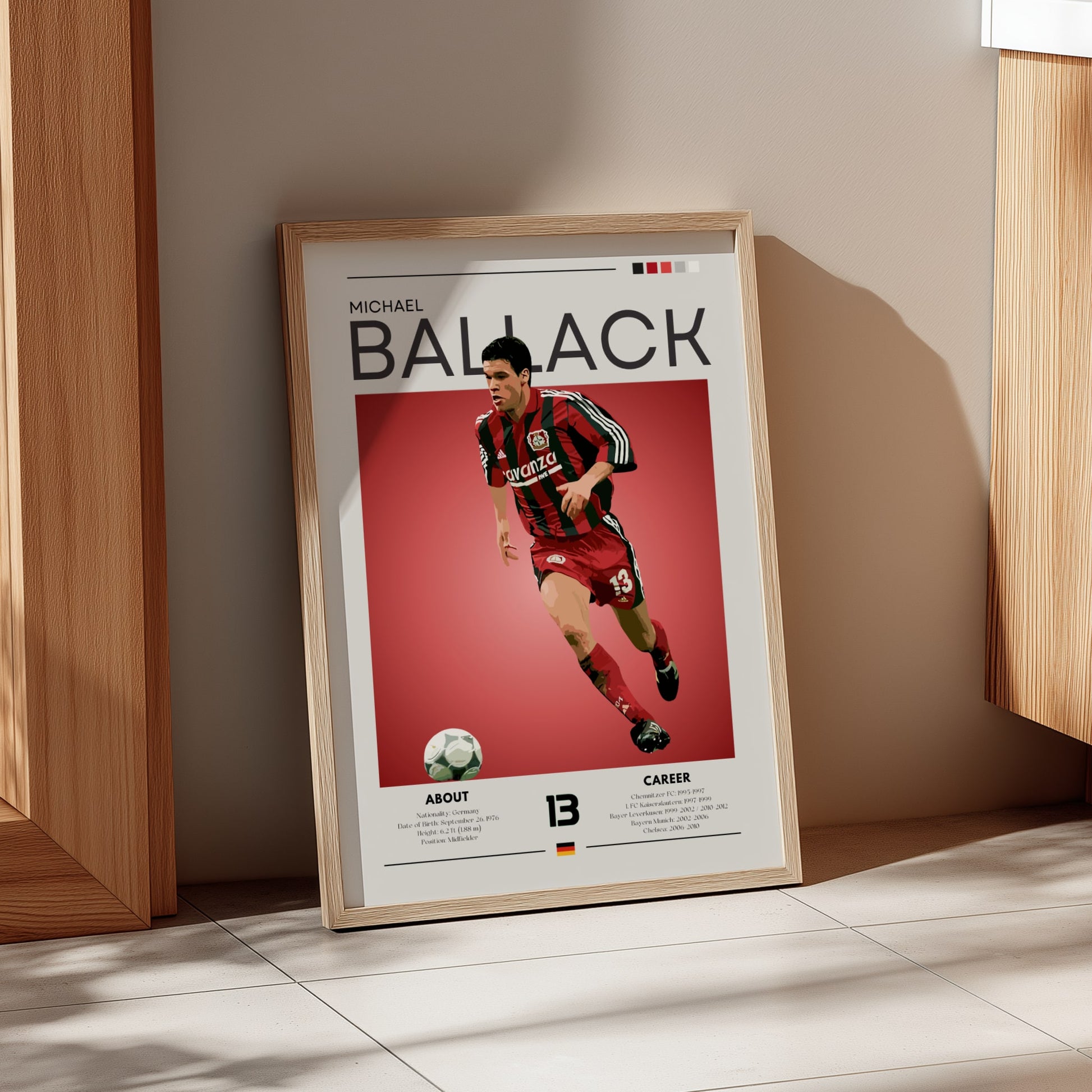 Framed poster of a soccer player in action on a red background, leaning against a wall.