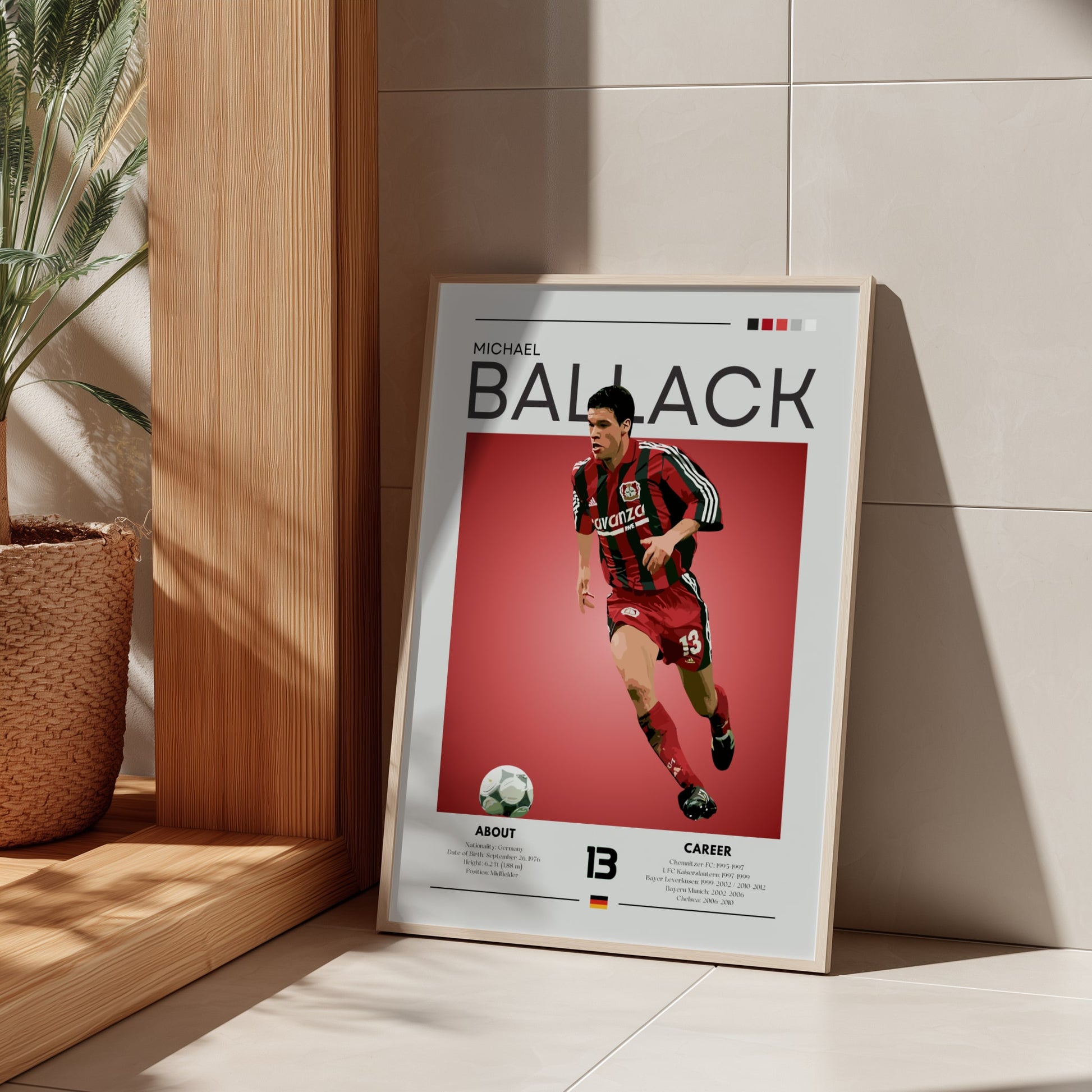 Framed poster of a soccer player with 'Michael Ballack' on a red background, leaning against a light-colored wall.