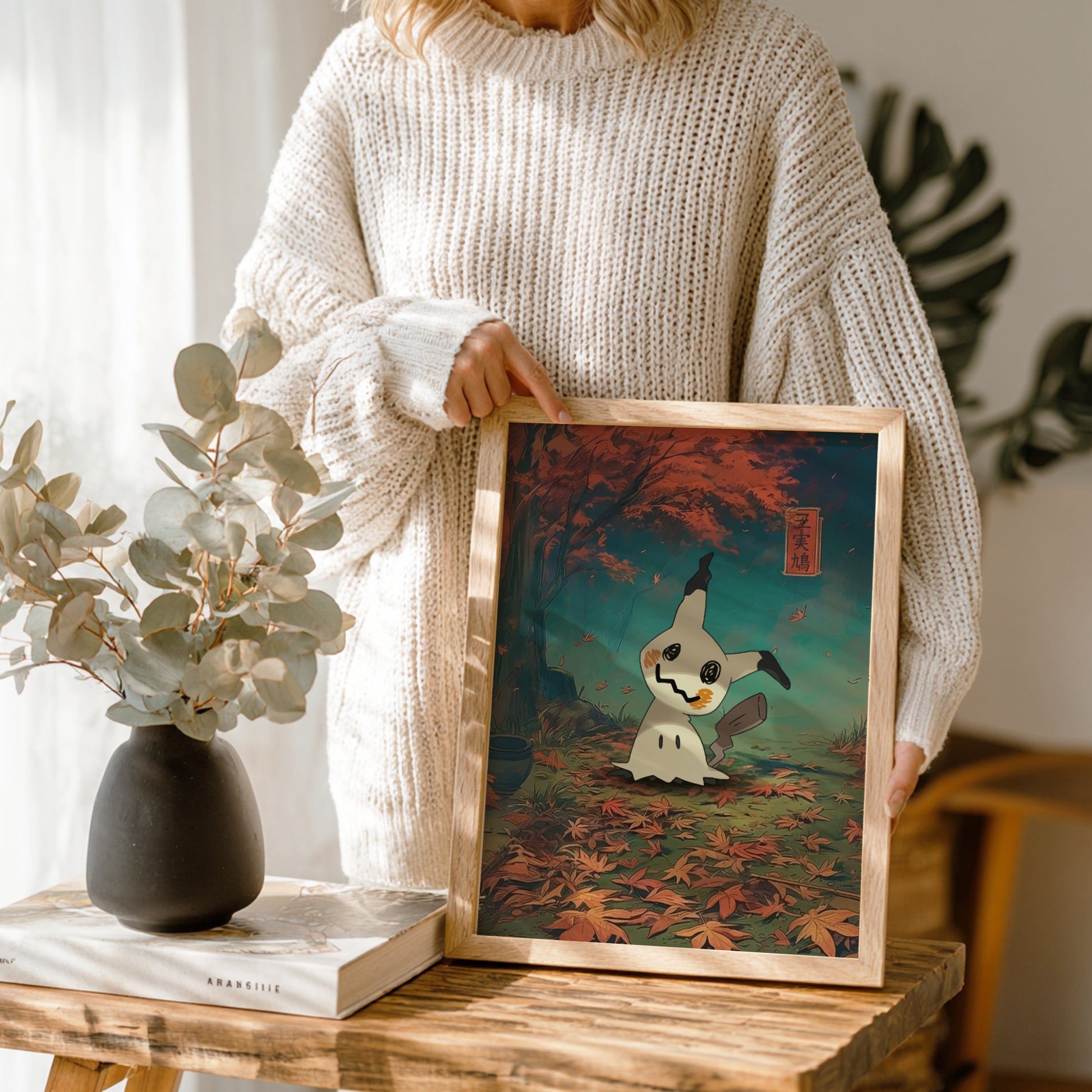 Person holding a framed artwork of Mimikyu Pokemon in a forest setting.