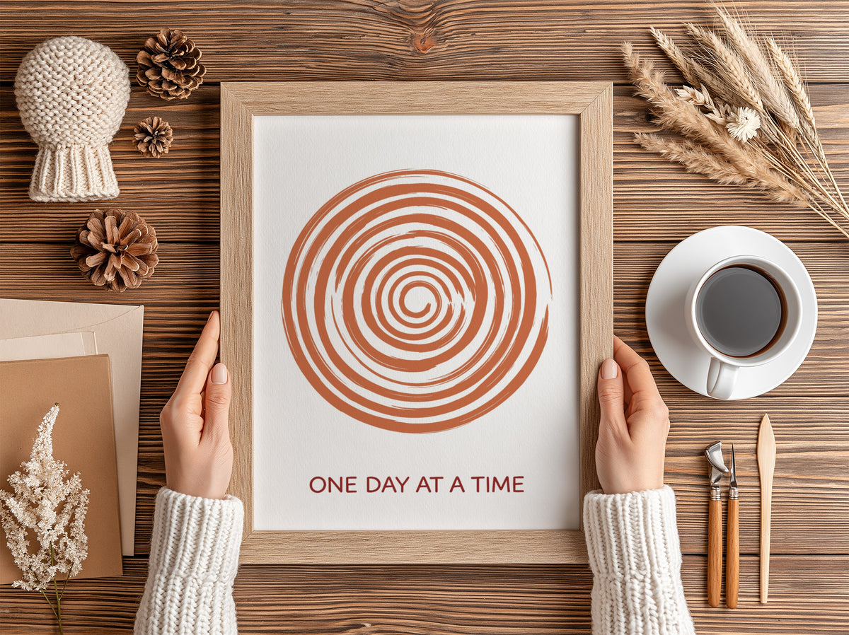 Motivational poster showing a burnt orange hand drawn spiral with One Day At A Time.