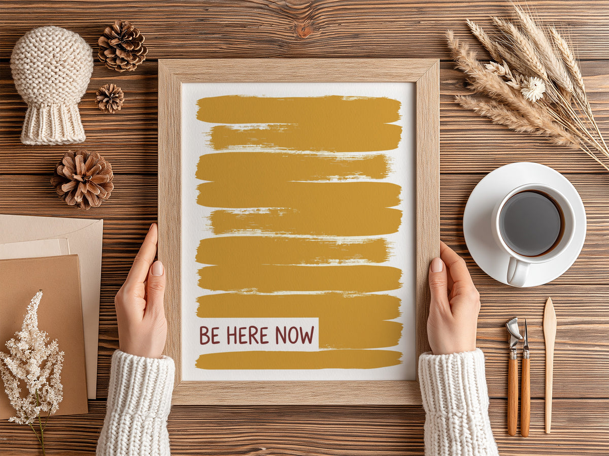 Motivational poster with yellow brushstrokes and the text Be Here Now in brown